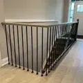 Black metal stair railing around an open stairwell in a bright hallway