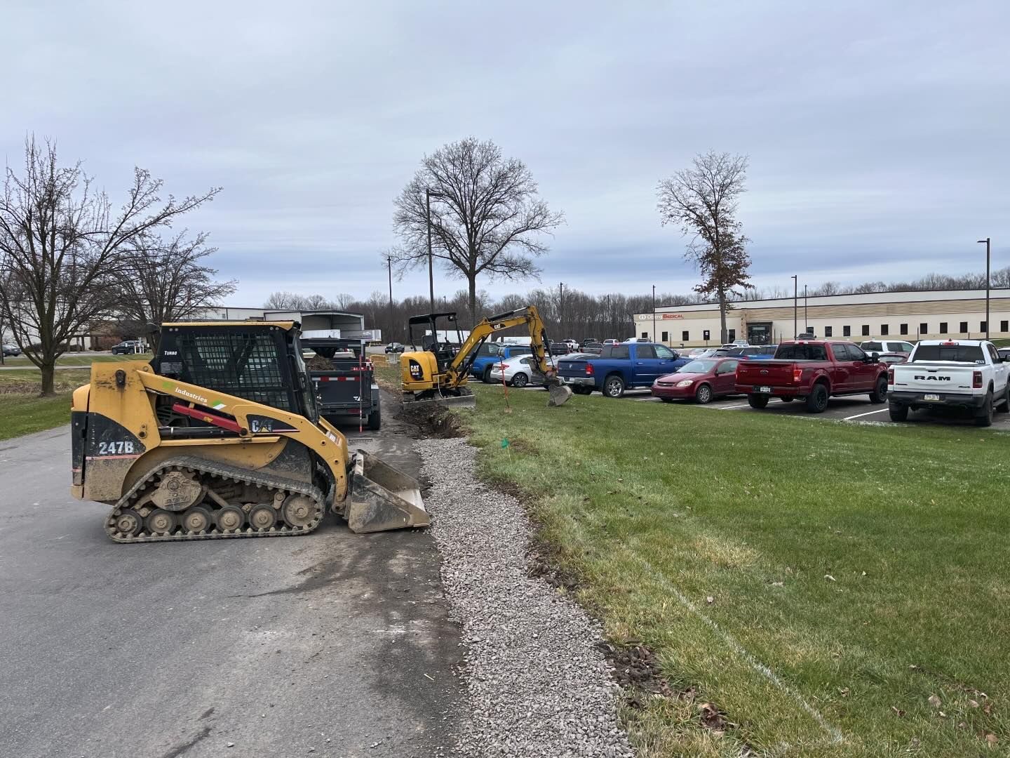 A bulldozer is driving down a road next to a parking lot.