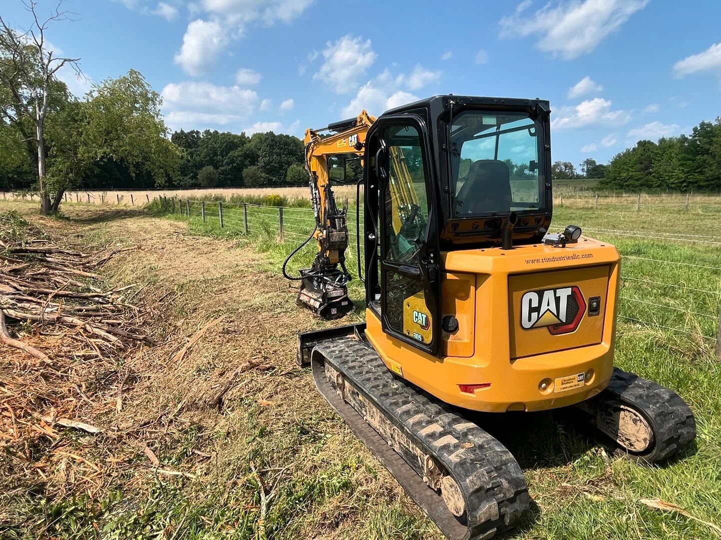 A yellow cat excavator is parked in a grassy field.