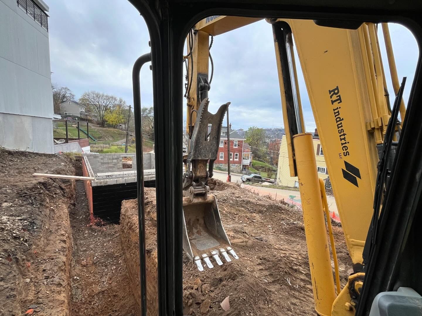 A yellow excavator is digging a hole in the ground.