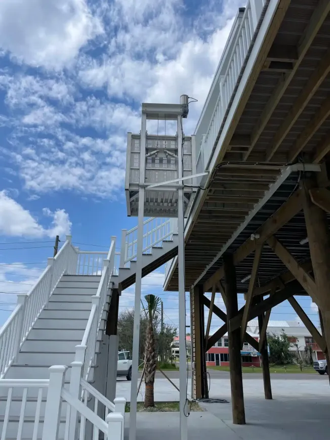 Staircase and elevated walkway with an accessibility elevator lift against a blue sky with clouds.