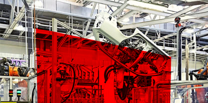 Car parts hanging in an industrial factory setting, with a red barrier in the foreground.