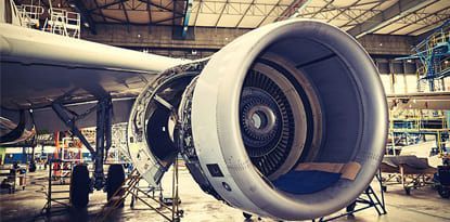 Jet engine being repaired inside a hangar.