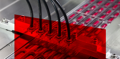 Automated machine filling red capsules, close-up view.