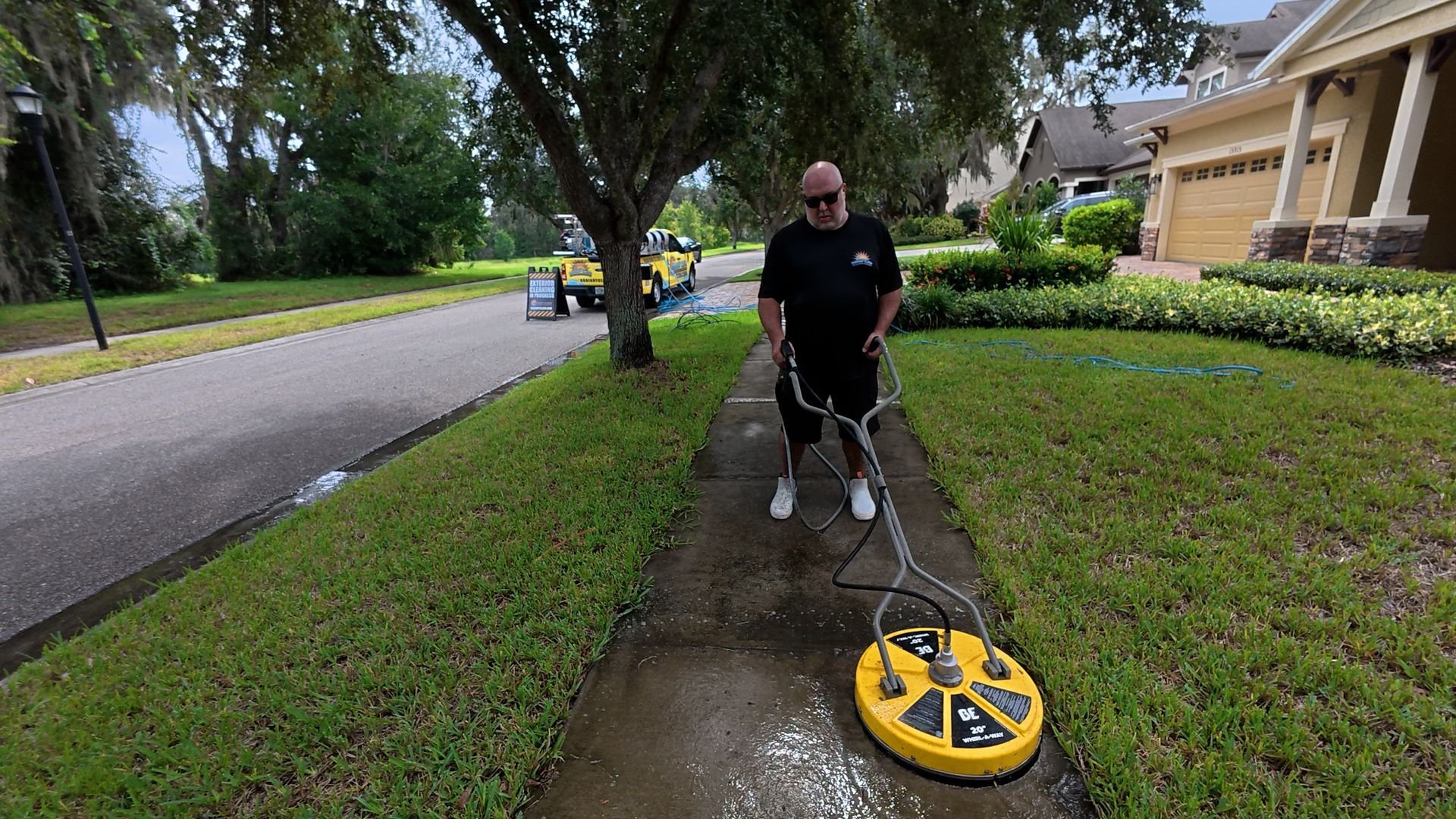 Radiant Clean pressure washing a sidewalk with a yellow surface cleaner