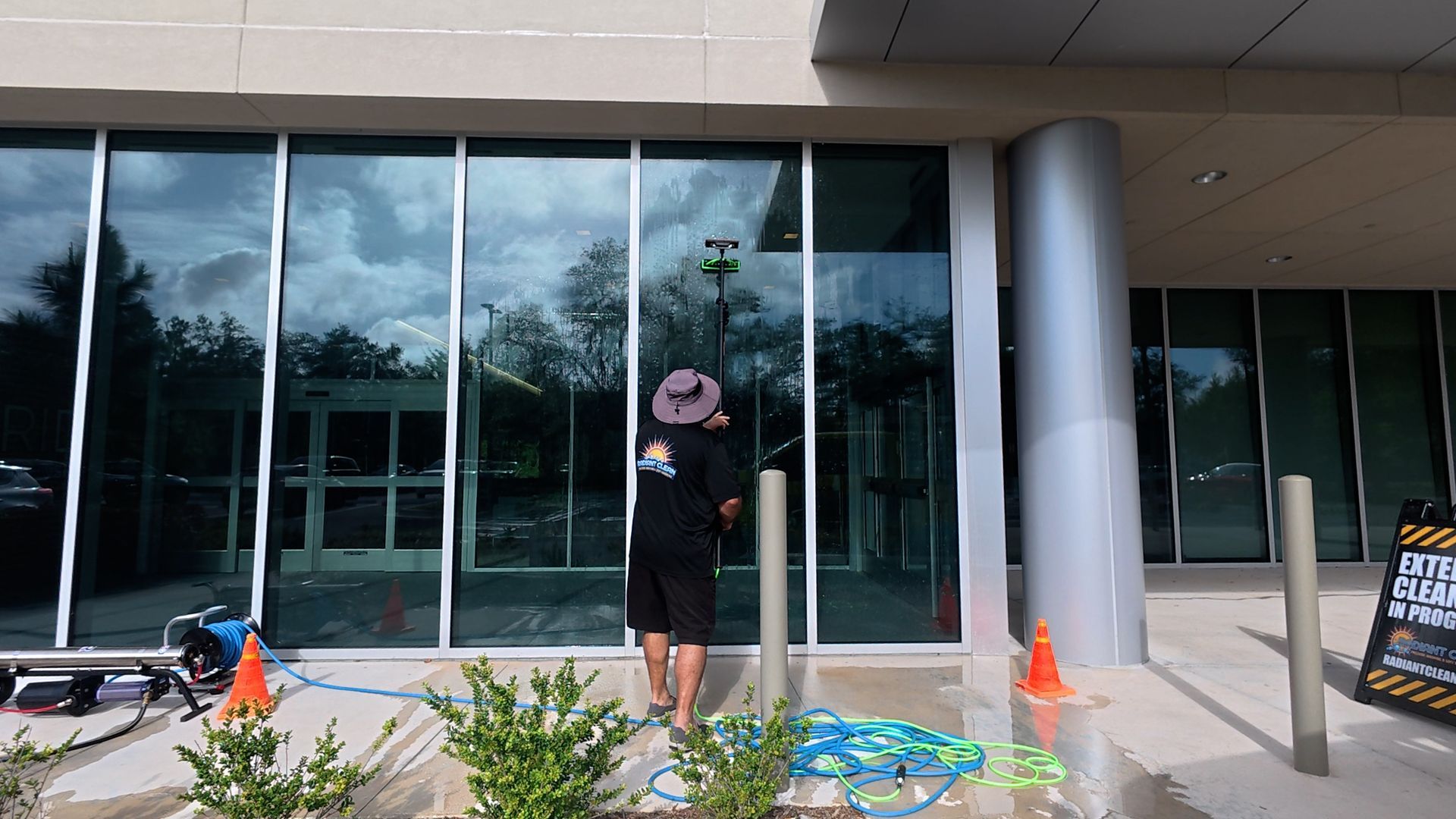 Person standing outside glass building with cleaning supplies and buckets near the entrance