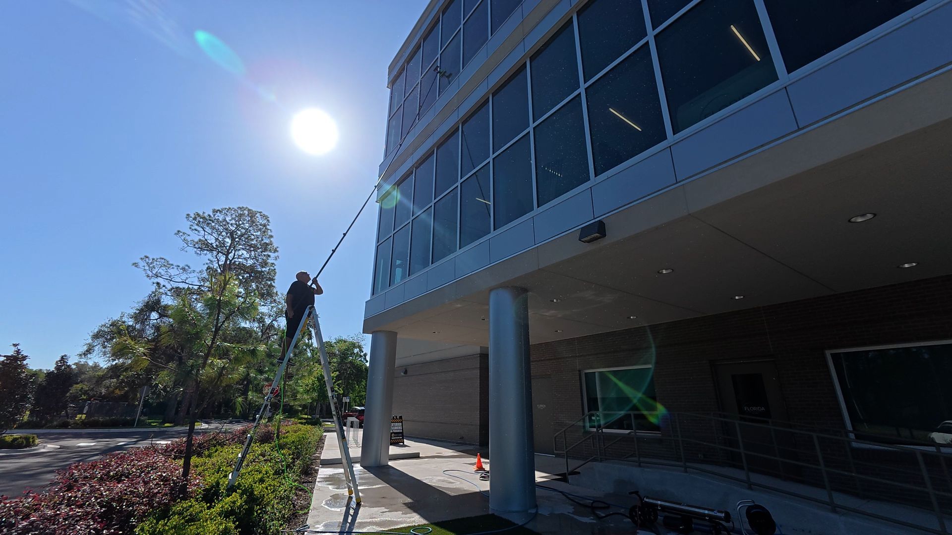 Washing tall windows on hospital building using water fed pole.