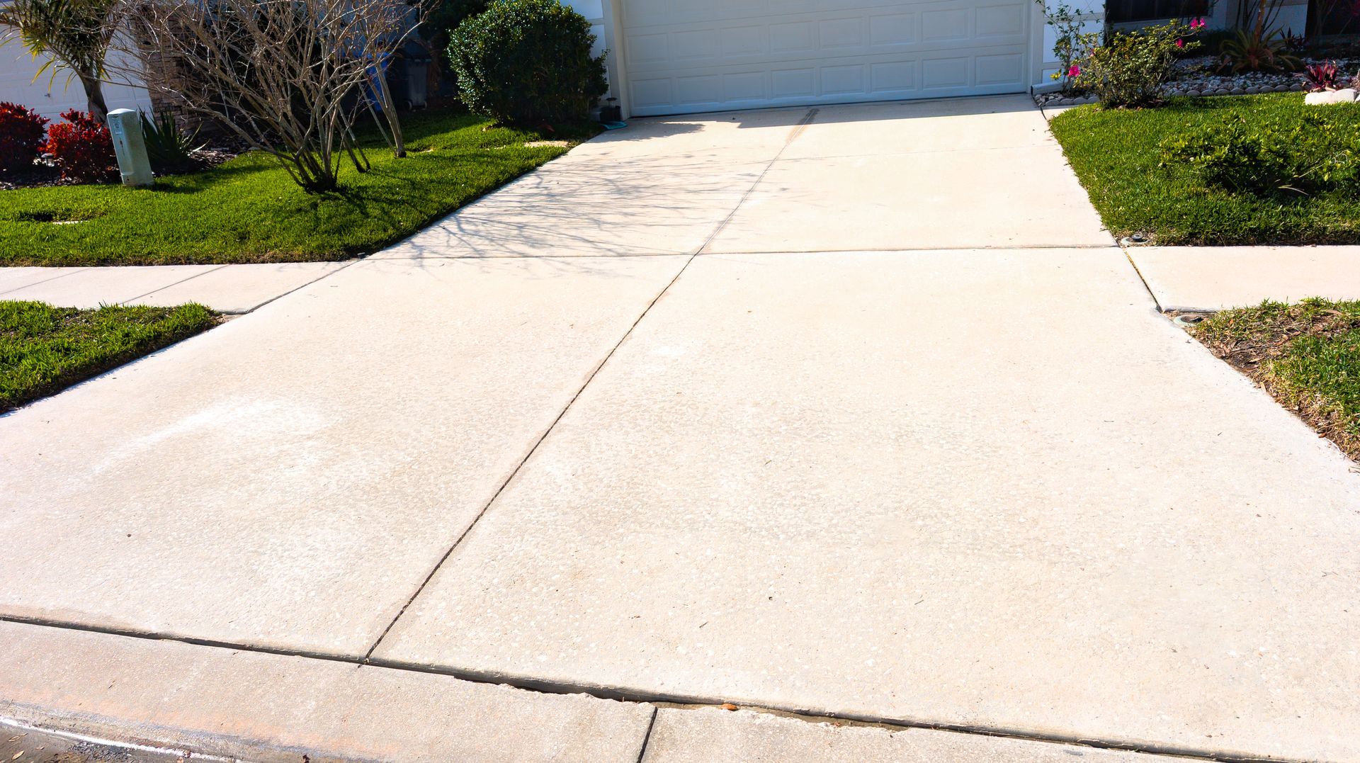 A concrete driveway leading to a house with a white garage door.