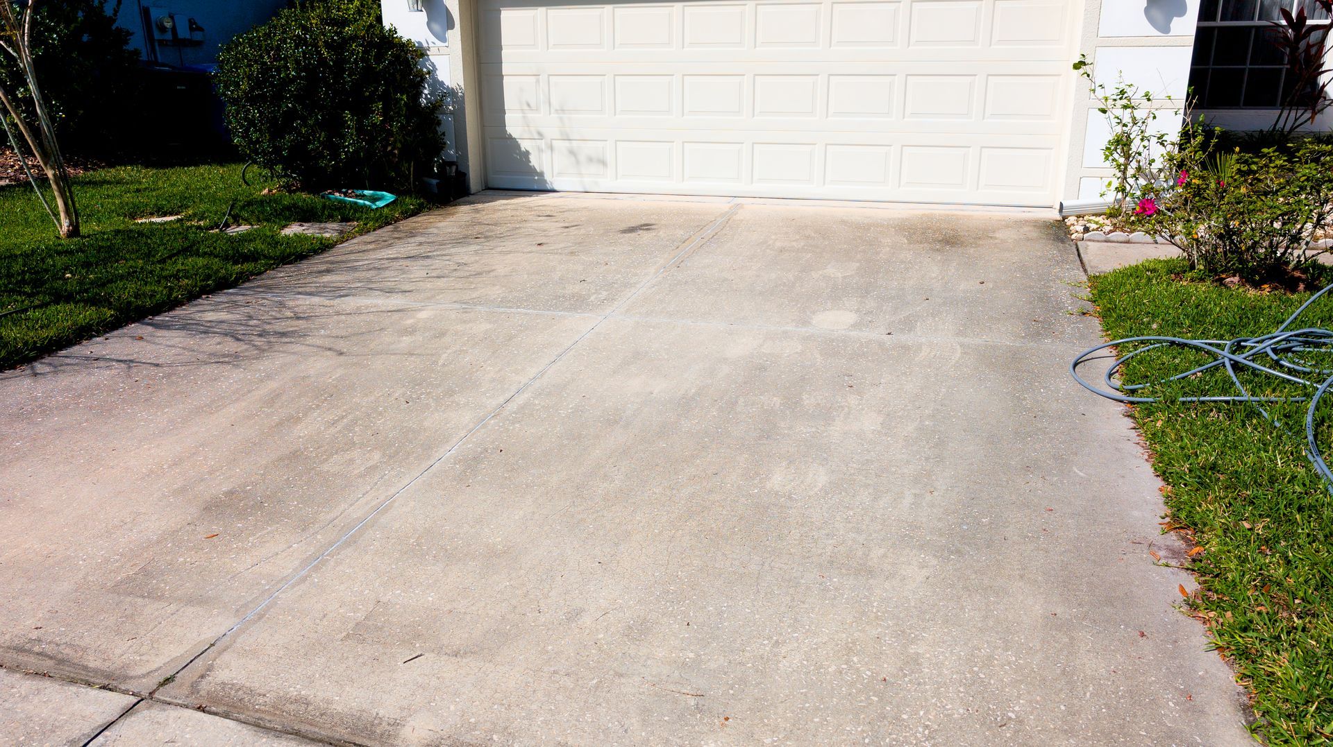 A concrete driveway leading to a white garage door.