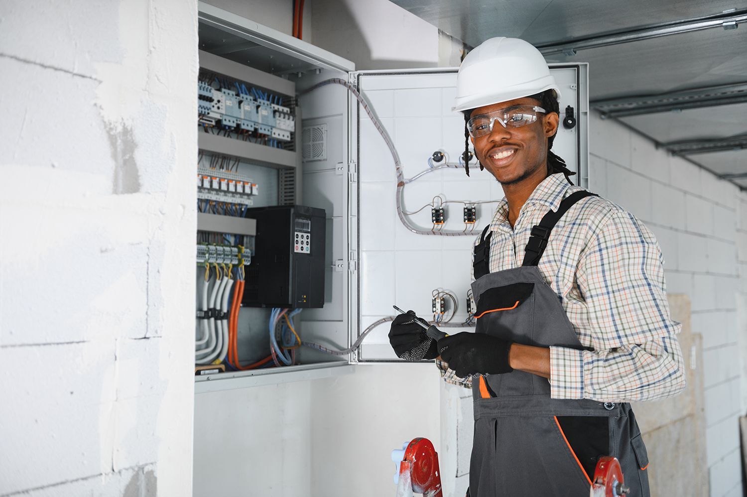 Commercial electrician working on control panel in building under construction. Commercial electrician working on control panel in building under construction.