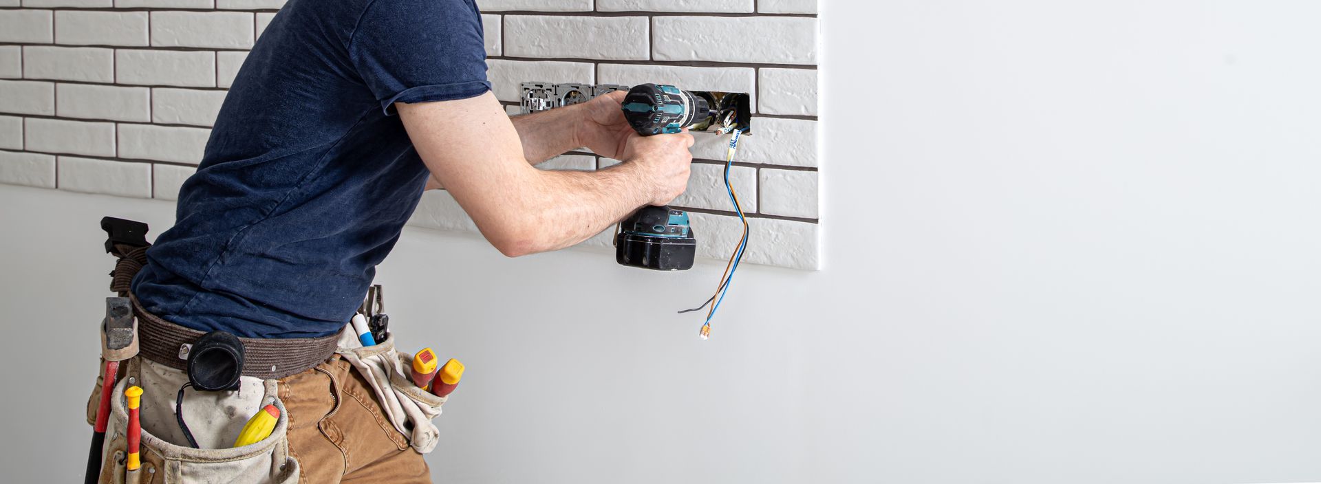 Electrician installing a wall outlet during professional work by electrical contractor services. Electrician installing a wall outlet during professional work by electrical contractor services.