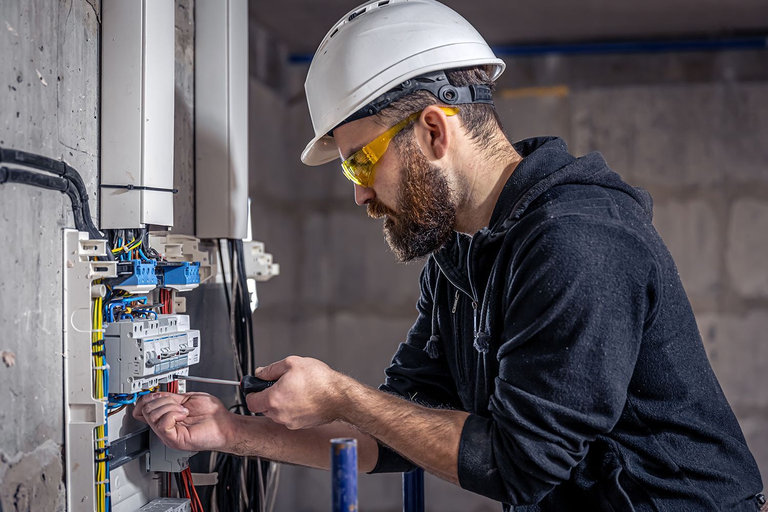A male professional from an electrician company works in a switchboard. A male professional from an electrician company works in a switchboard.