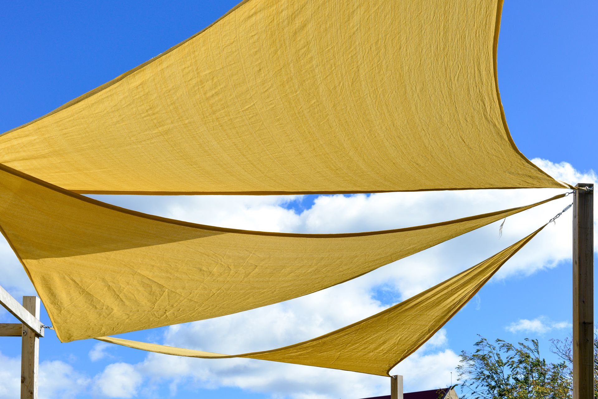 View of a yellow shade sail against a blue sky with some clouds. View of a yellow shade sail against a blue sky with some clouds.