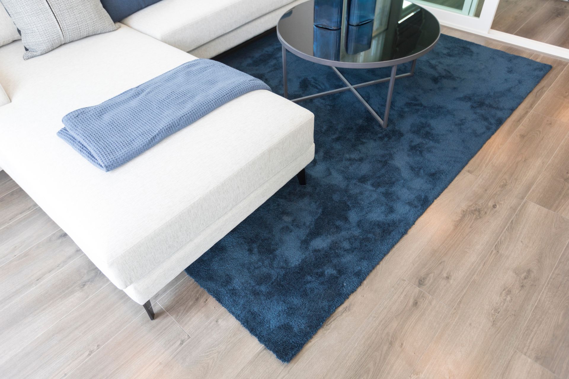 A living room with a couch , coffee table , and blue rug.