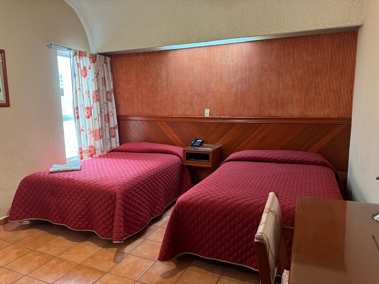 Una habitación de hotel con dos camas, un escritorio y una ventana.