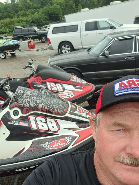 A man wearing a hat is standing in front of a row of jet skis.