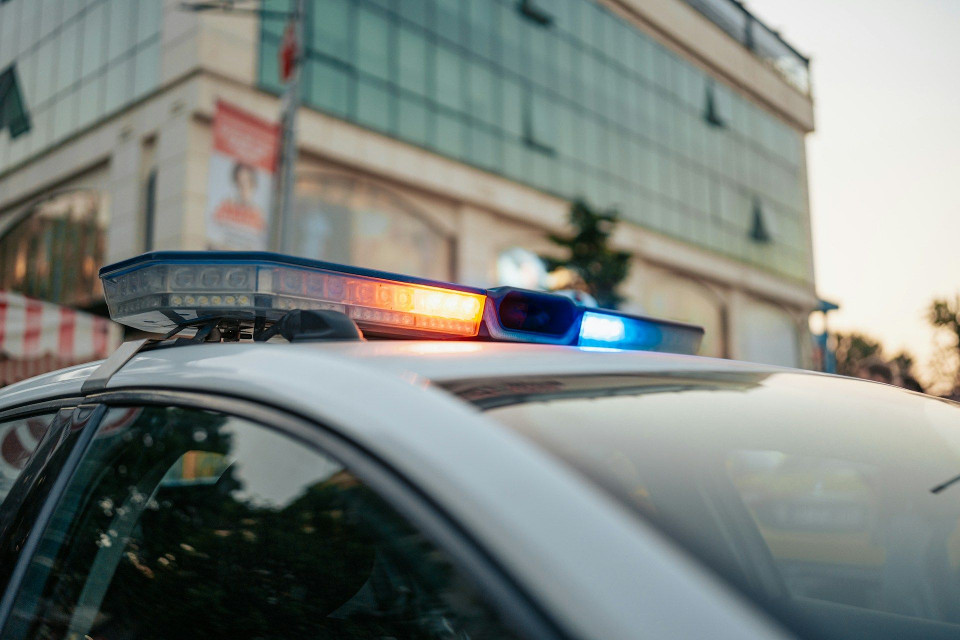 A police car is parked in front of a building with its lights on.