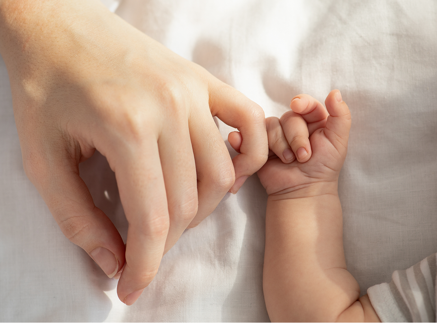 A close up of a person holding a baby 's hand.
