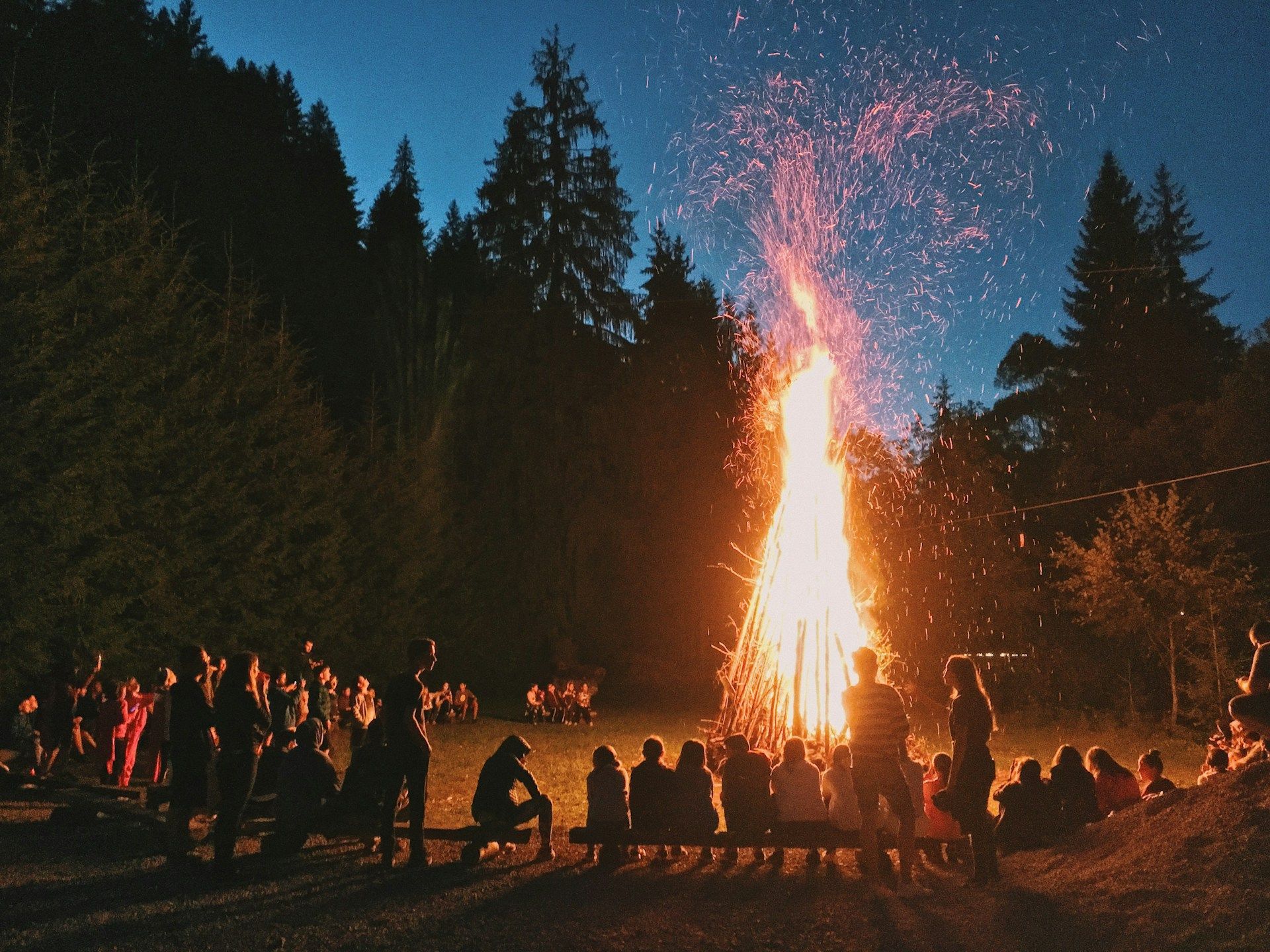 A group of people are sitting around a campfire at night
