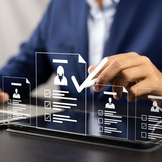 Person in suit using stylus on tablet with candidate profiles, selecting a profile.