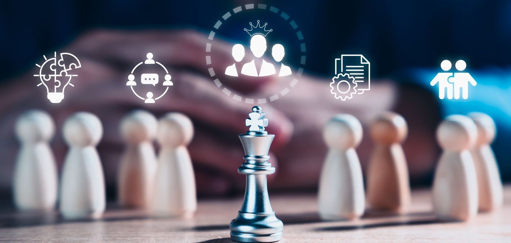 Chess king piece in front of wooden figures with teamwork icons, symbolizing leadership and strategy.