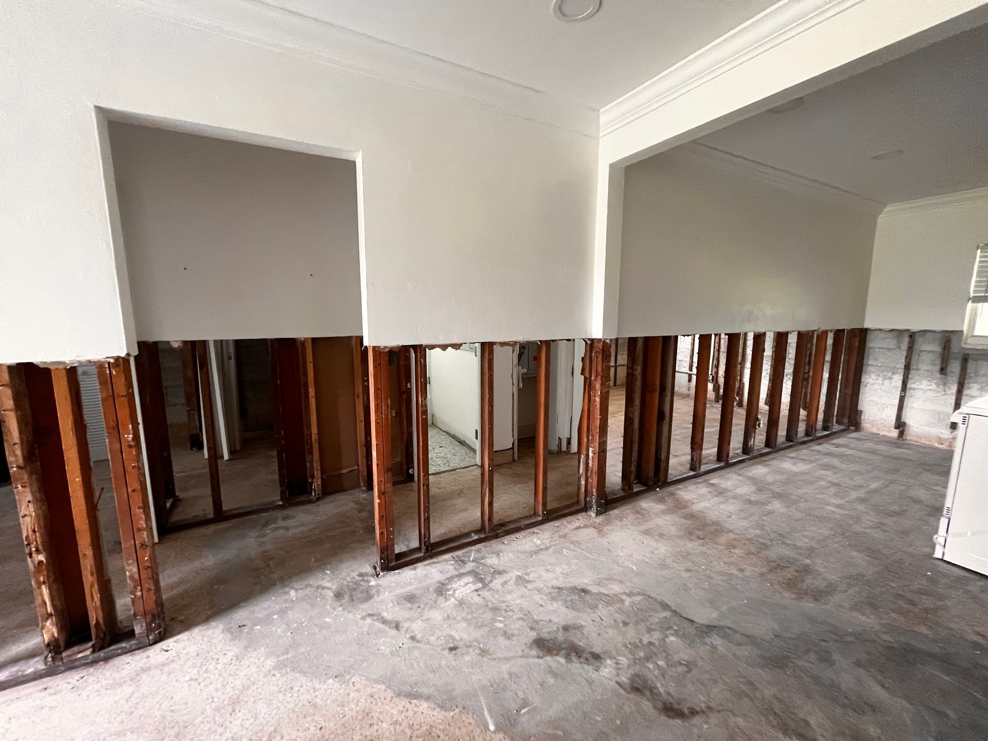Damaged interior wall with exposed studs and plaster removed during renovation