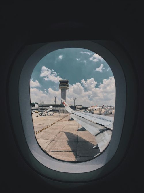 Airport runway seen through an airplane window under a blue sky with scattered clouds