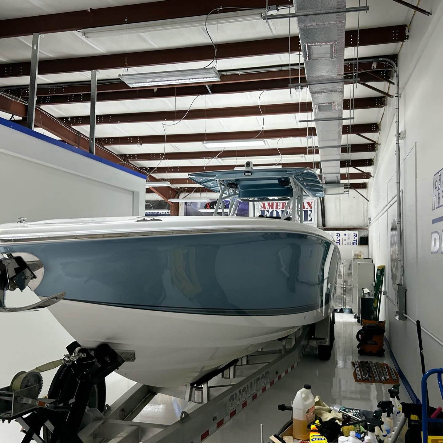 Blue-and-white boat on a trailer inside a warehouse workshop
