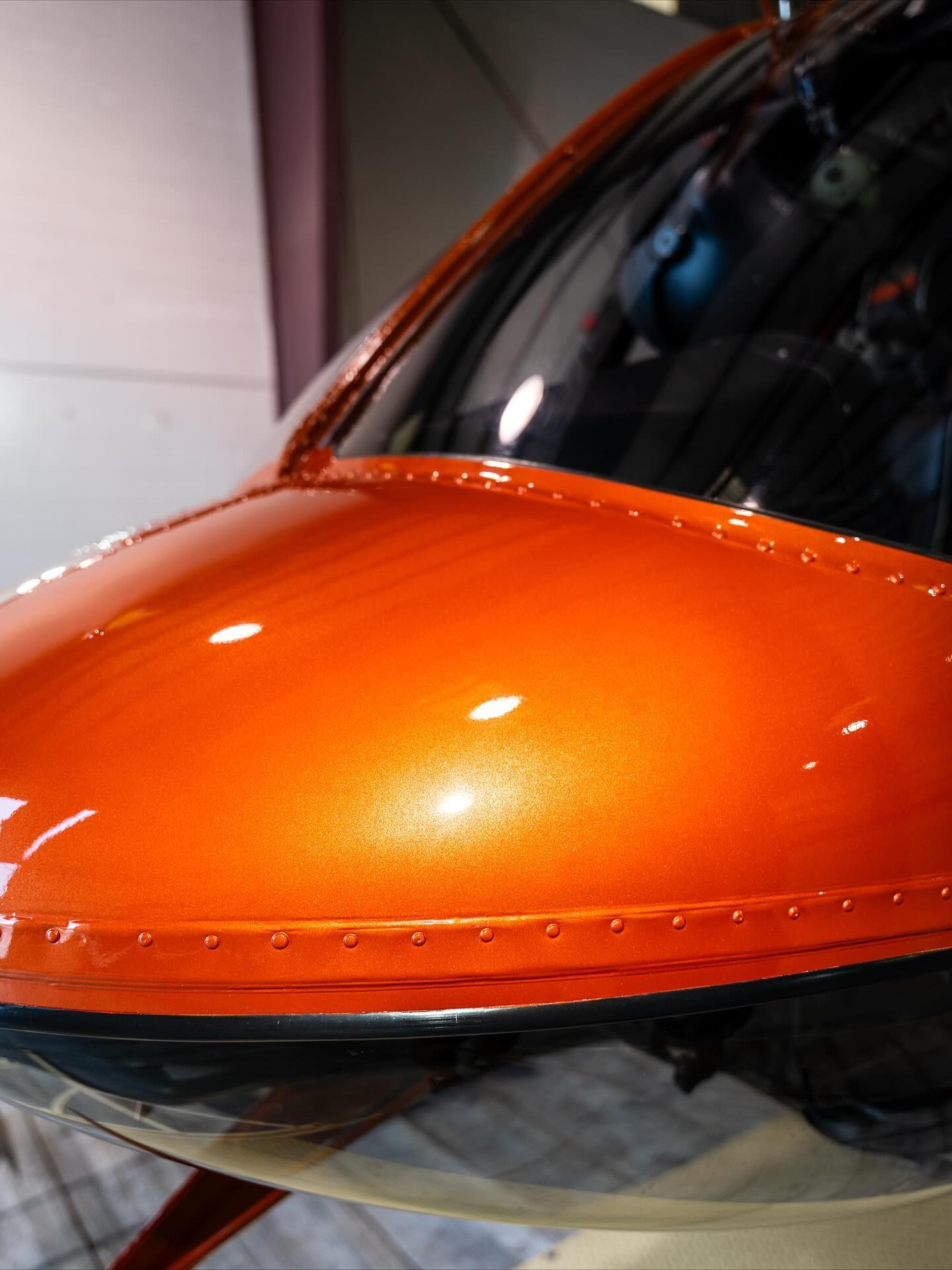 Orange and black glossy aircraft nose cone with reflections, close-up view