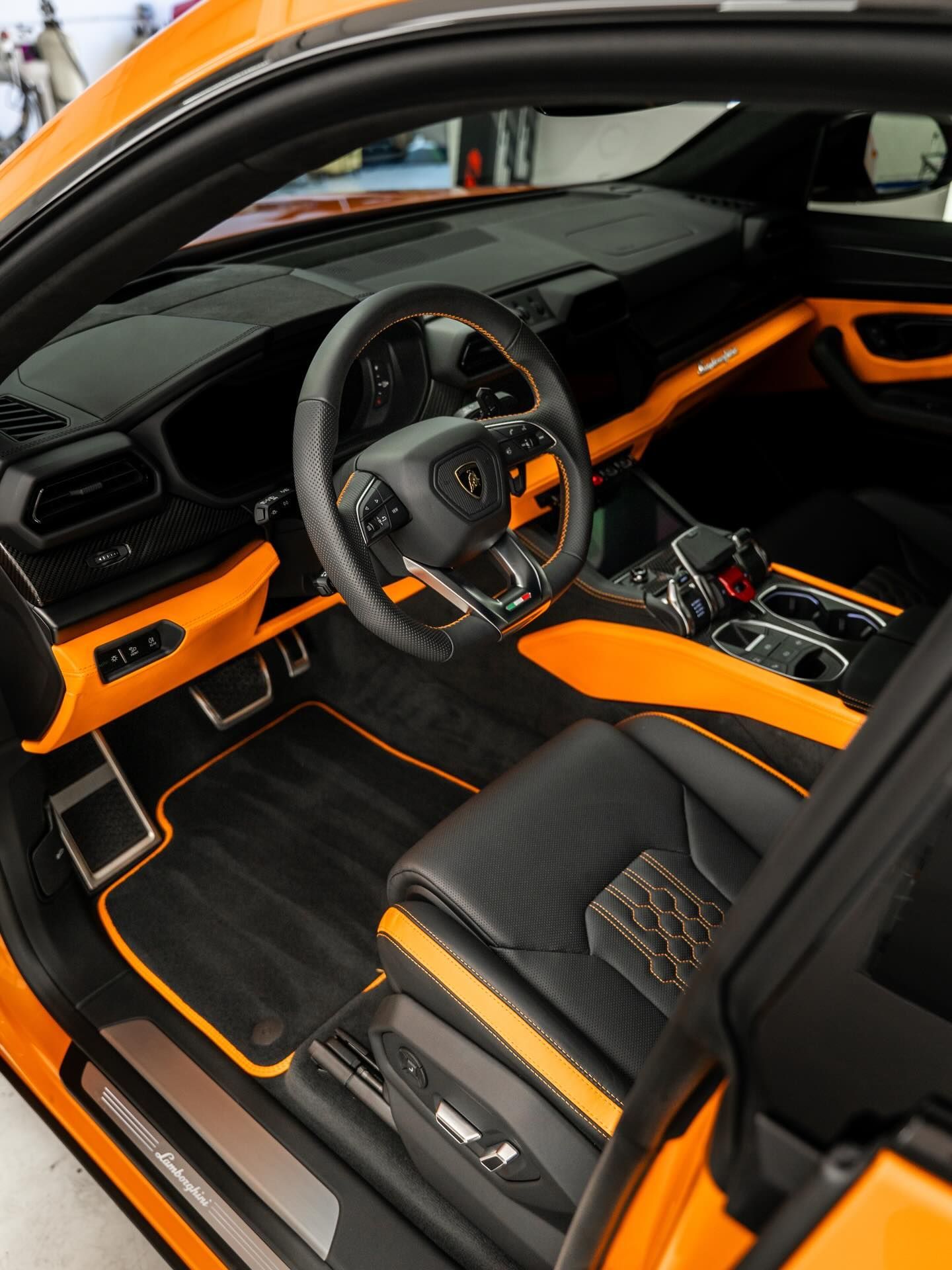 Black and orange luxury sports car interior with leather seats, steering wheel, and center console visible