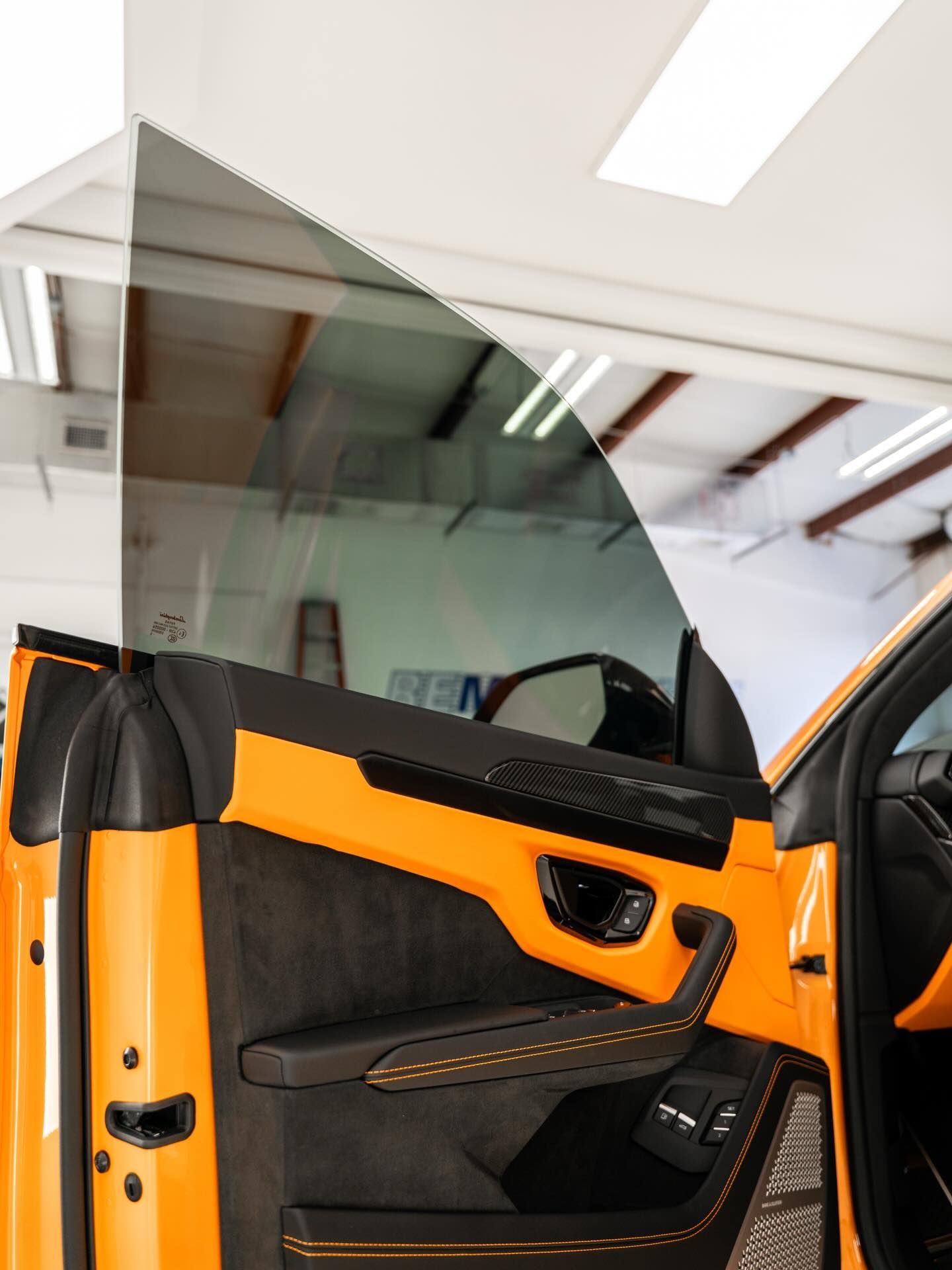 Open car door with orange and black interior, shown in a bright garage.