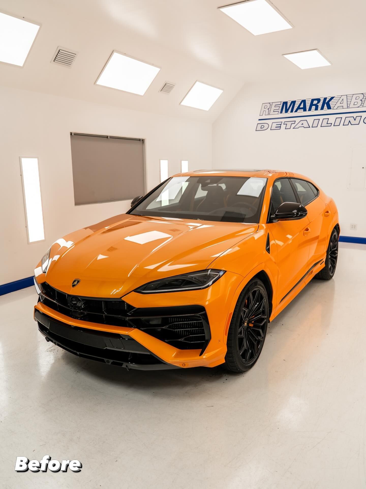 Orange sports SUV in a bright showroom, angled front view with black wheels and a glossy finish