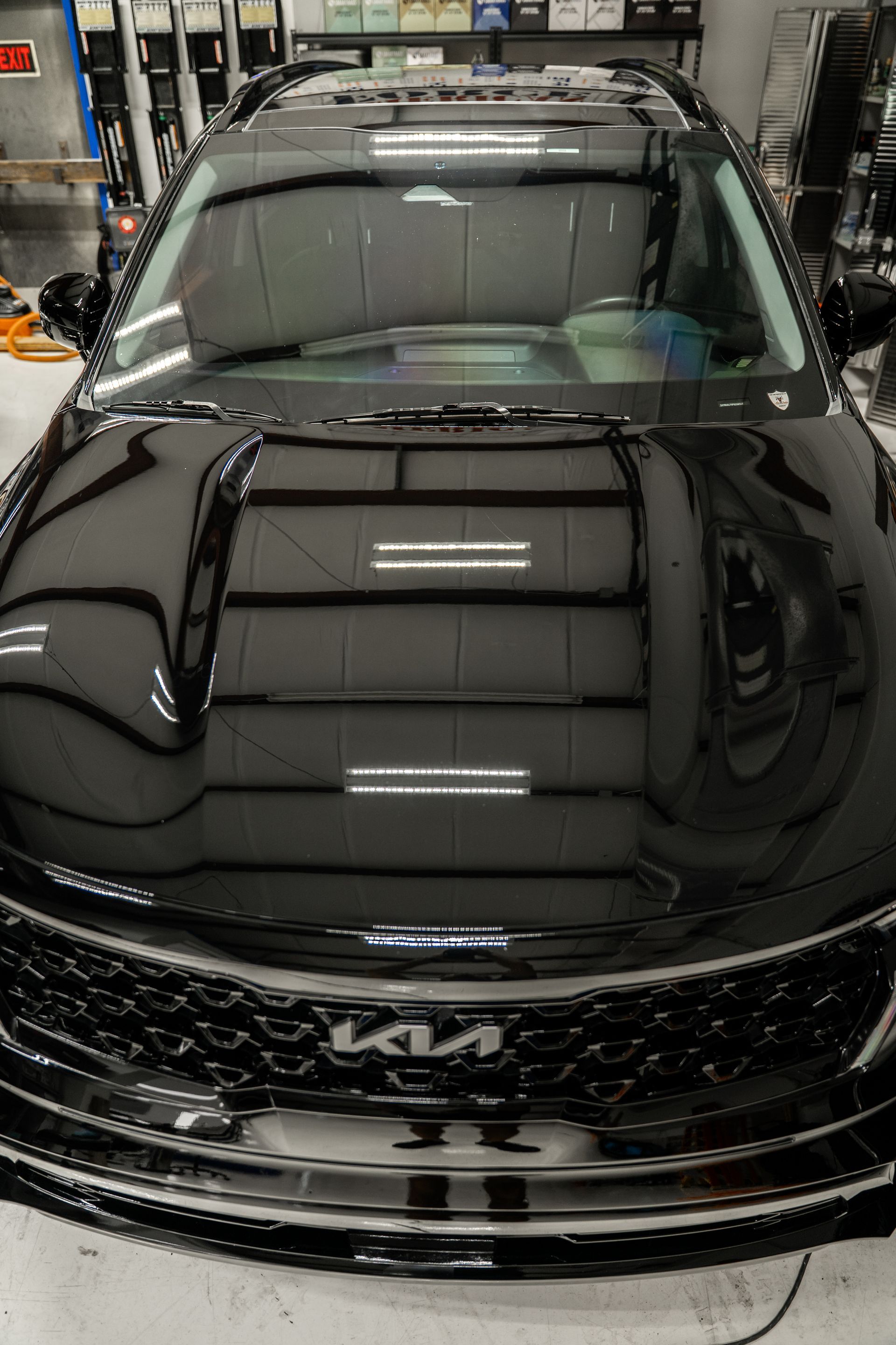 Black Kia SUV in a garage, front view with glossy hood reflection