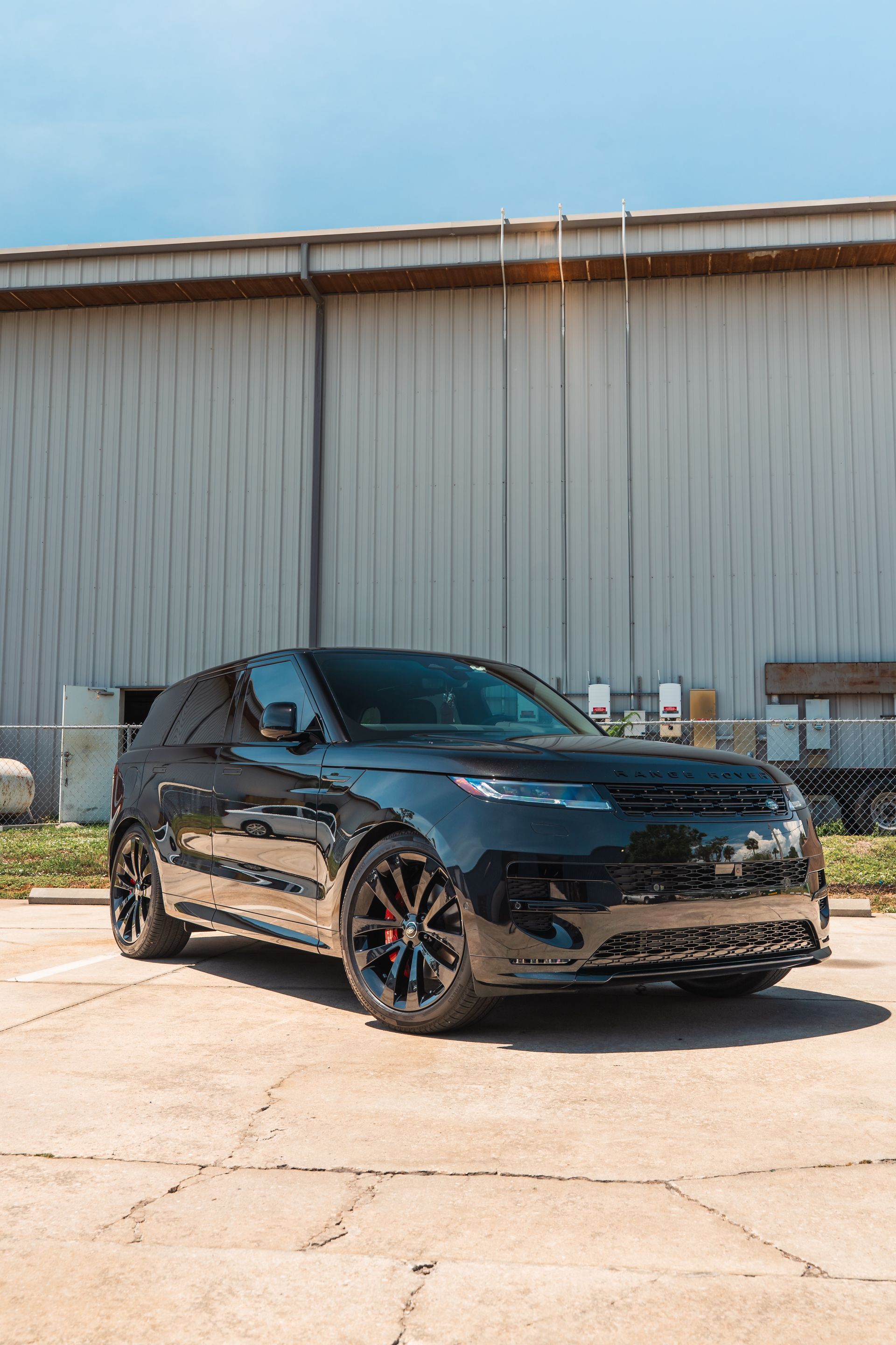 Black compact SUV parked outdoors in front of a large corrugated metal building