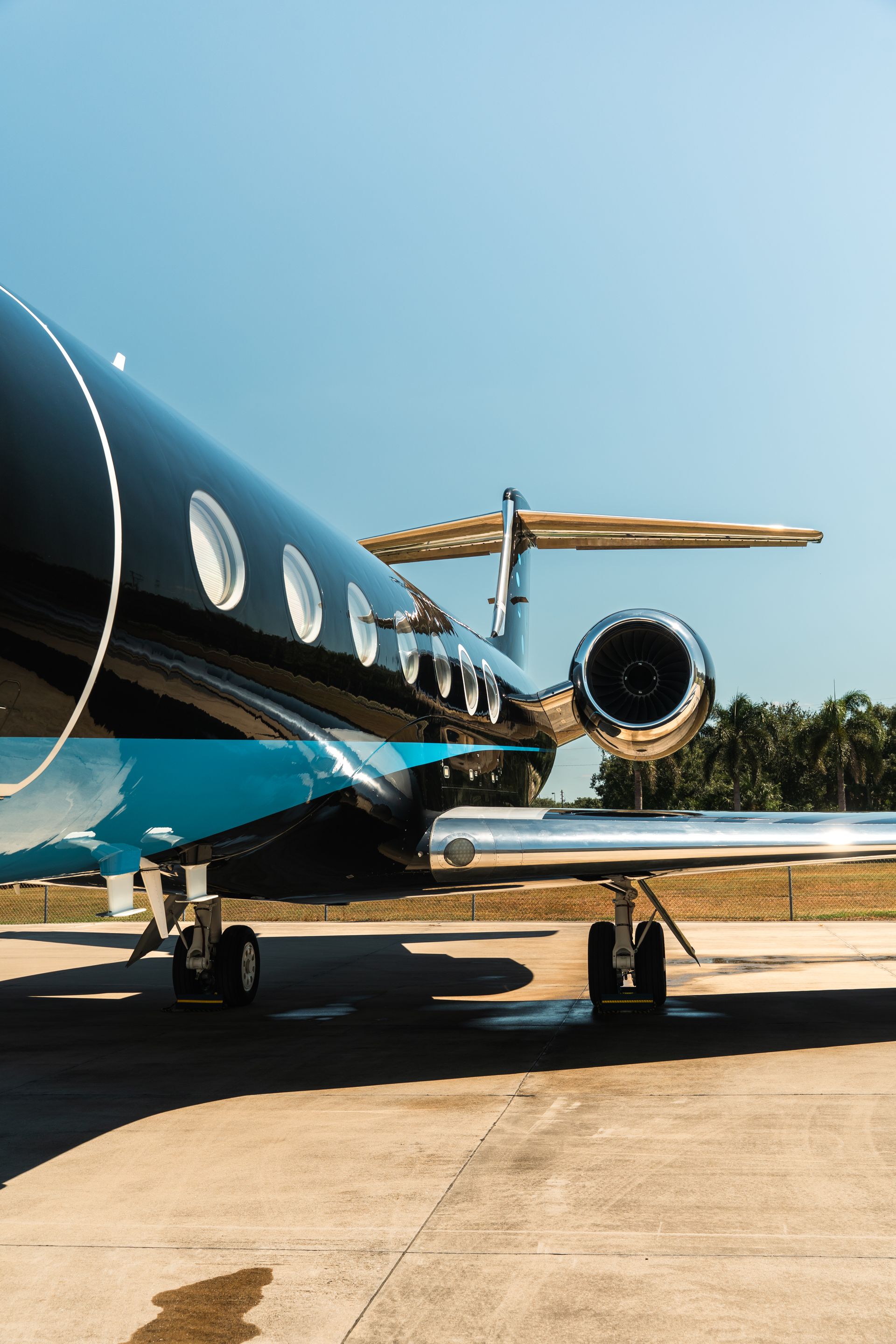 Blue private jet parked on a tarmac under a clear sky