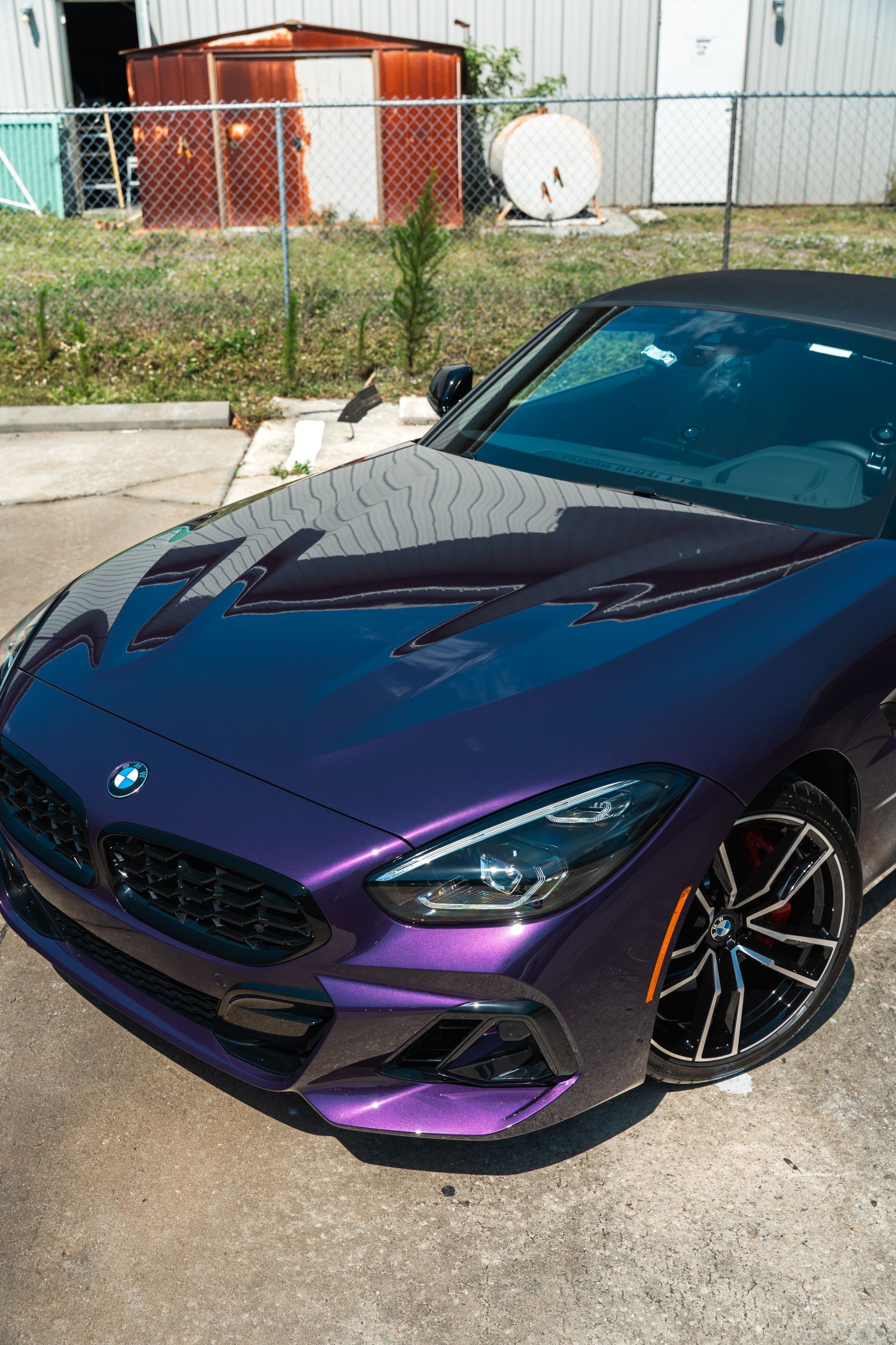 Purple BMW parked outdoors on a driveway, front view with glossy finish and black rims
