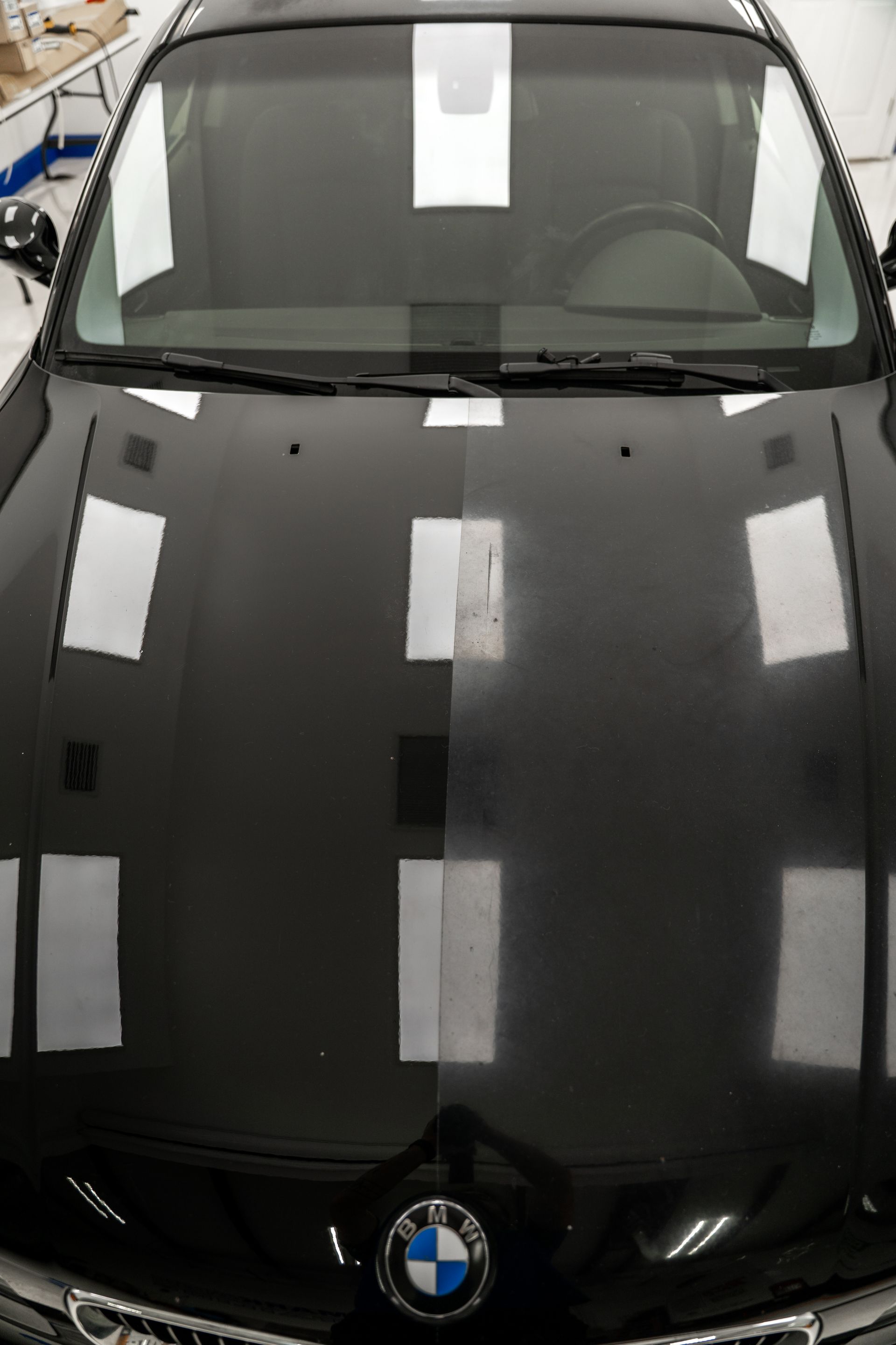 Front view of a black BMW car with reflections on the hood in a showroom-like setting