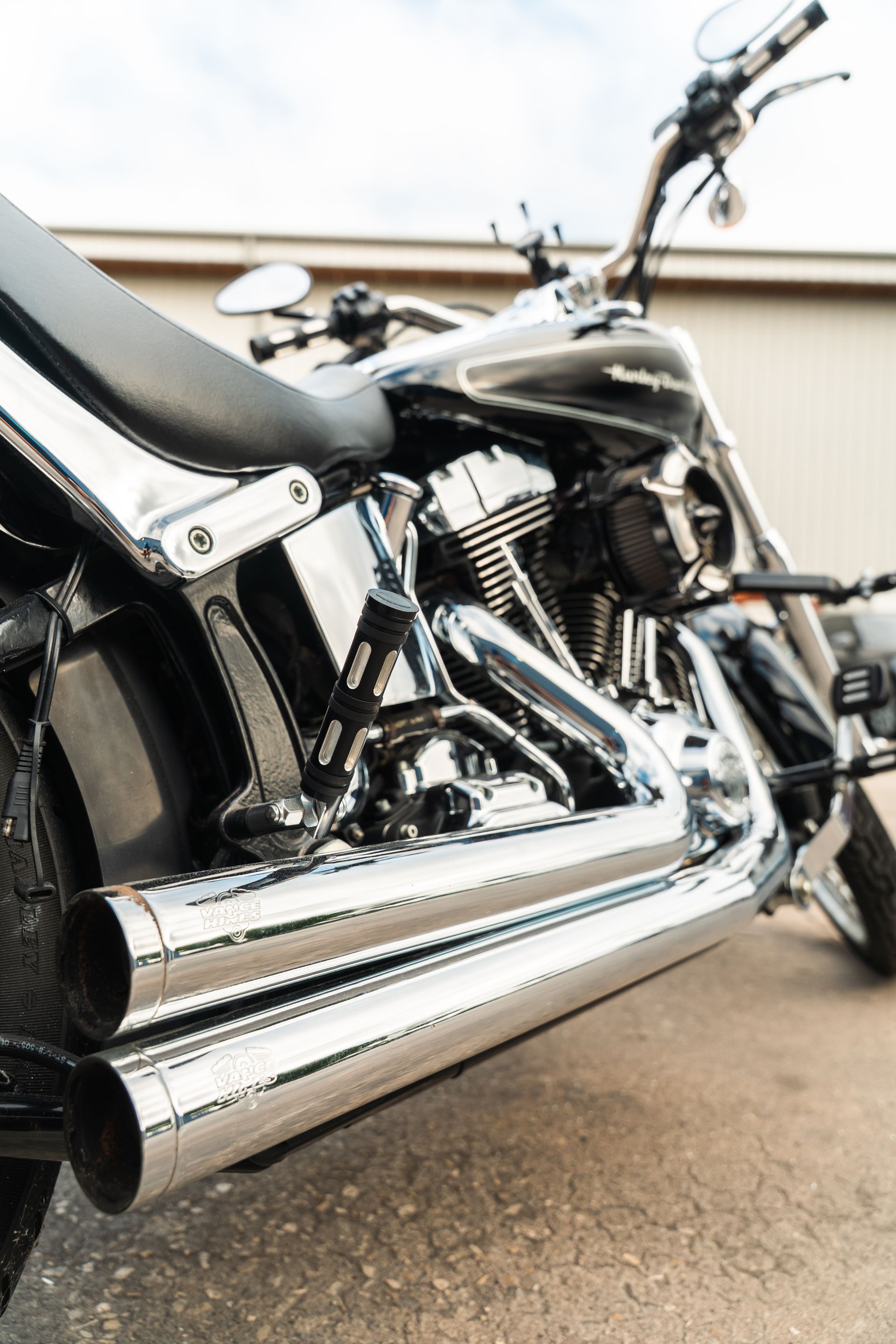 Close-up of a black cruiser motorcycle with chrome exhaust parked outdoors.