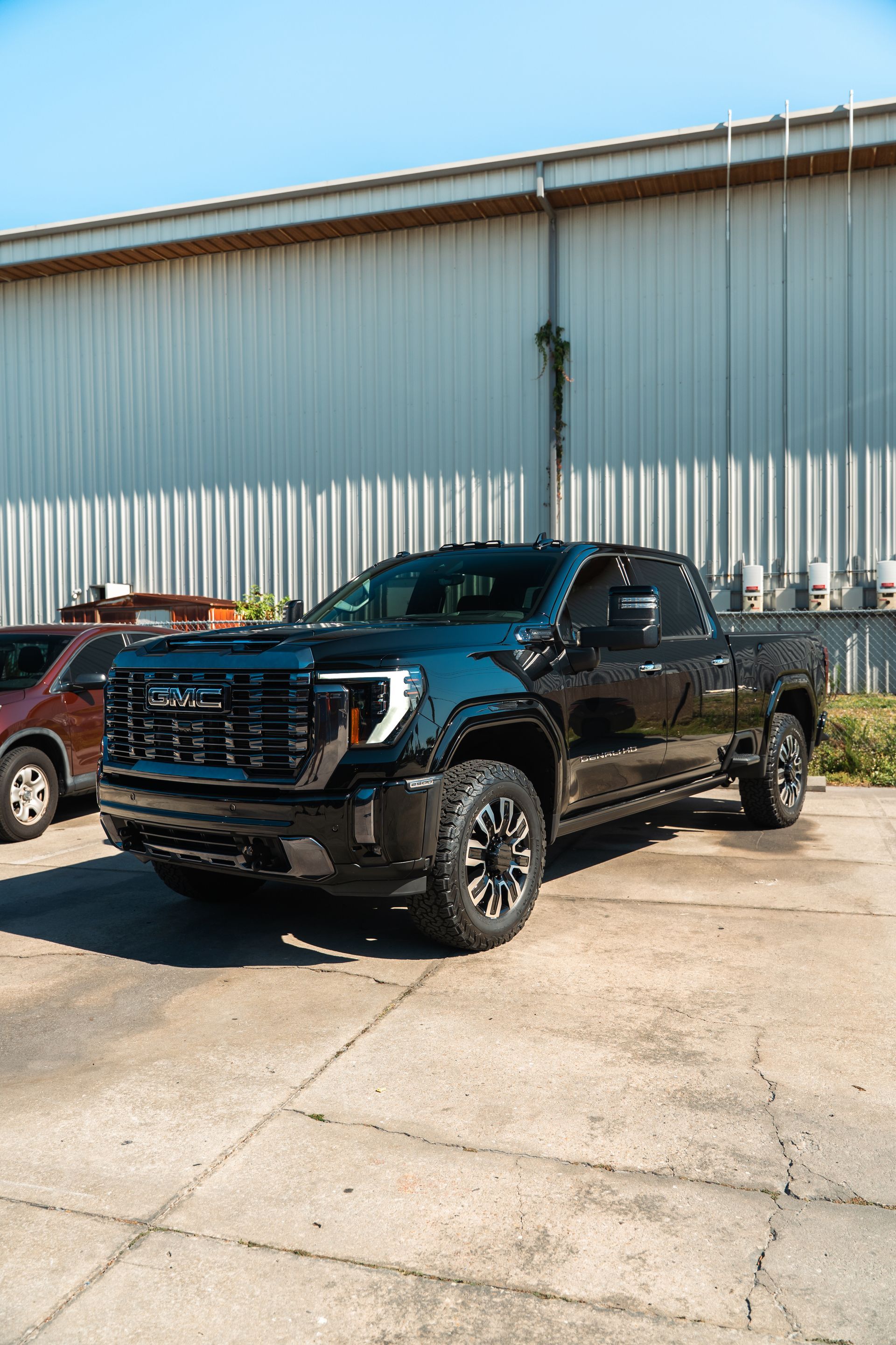 Black pickup truck parked outside a warehouse on a sunny day