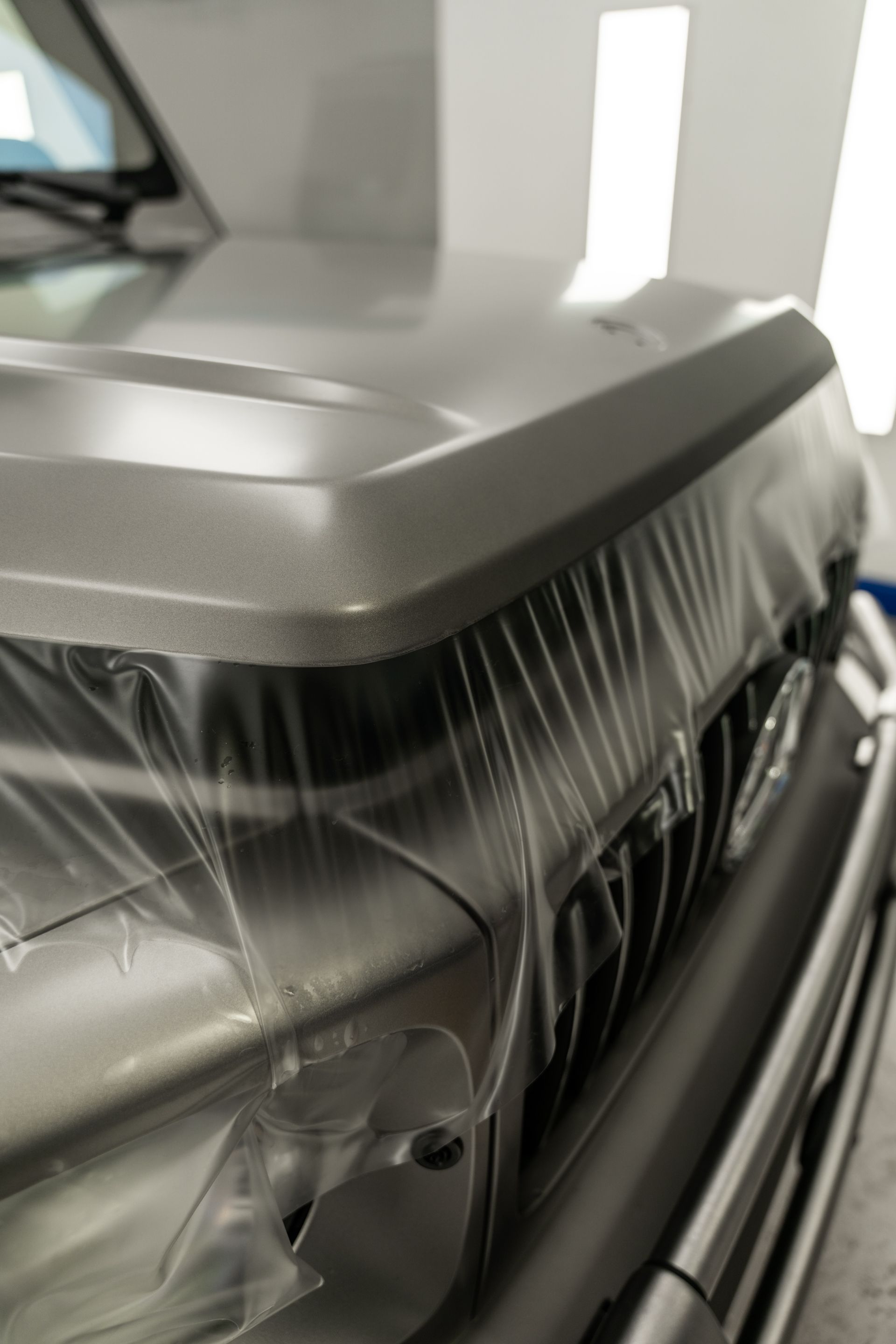 Black SUV front corner wrapped in protective plastic during transport or detailing