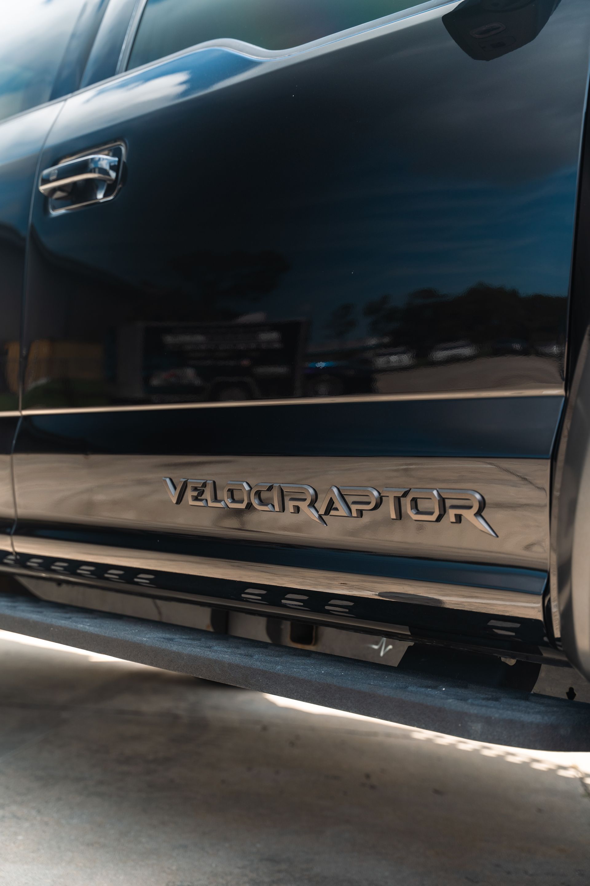 Close-up of a black Ford Raptor truck door and running board with V8 lettering