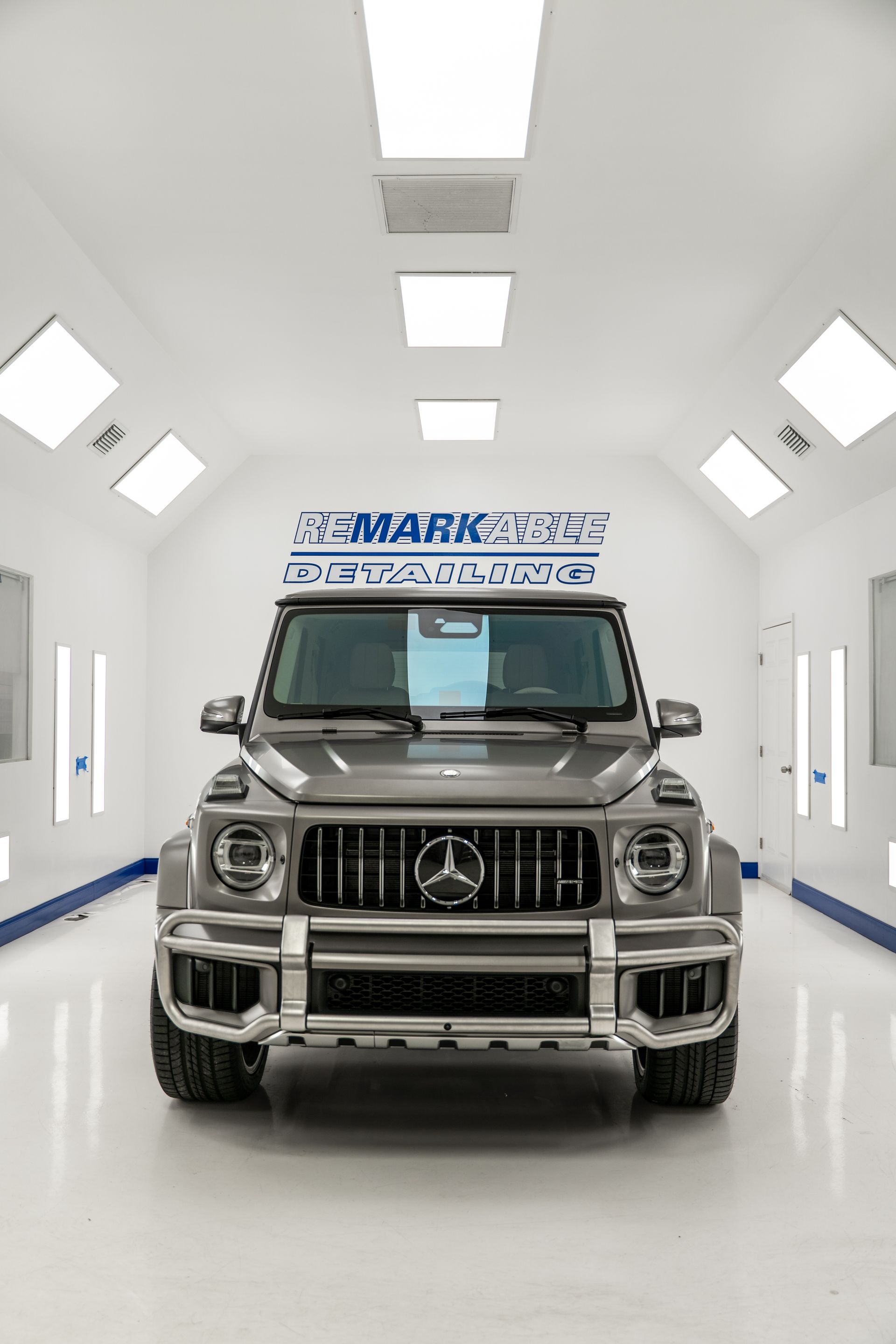 Mercedes-Benz SUV in a bright white showroom with ceiling lights and blue accents