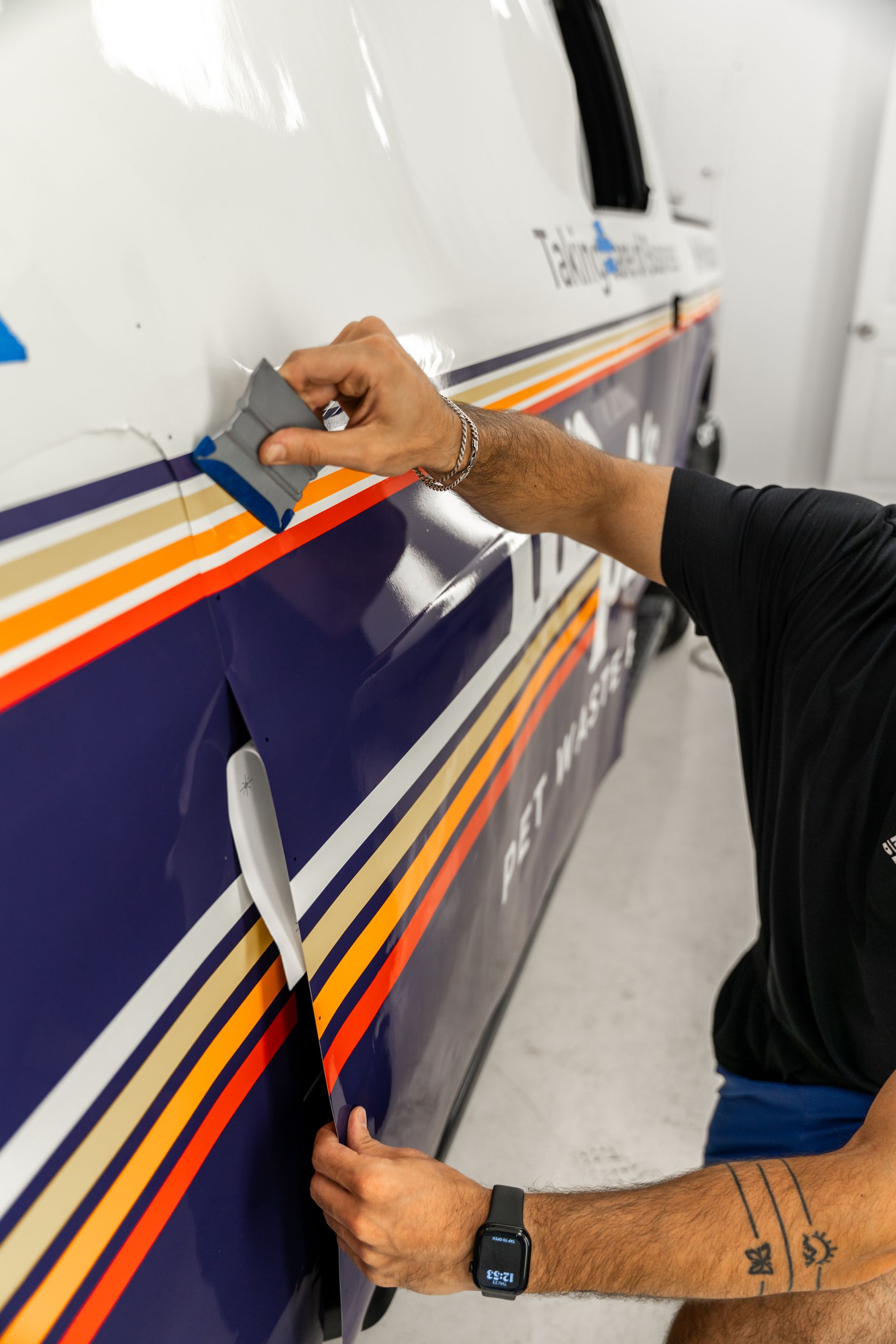 Hands applying red tape to a striped aircraft fuselage panel in a workshop
