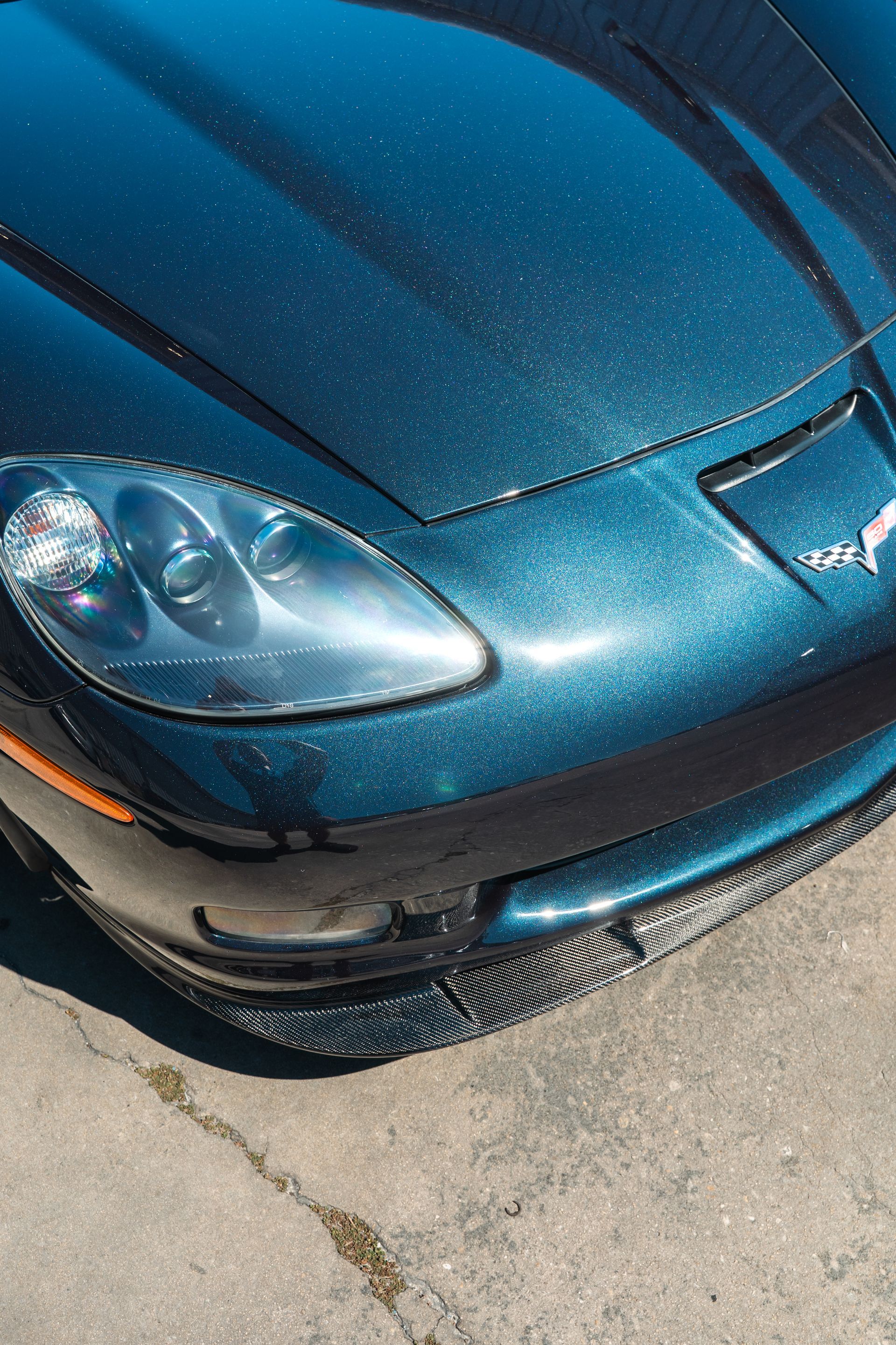 Front view of a blue sports car parked on pavement, showing the hood and headlights