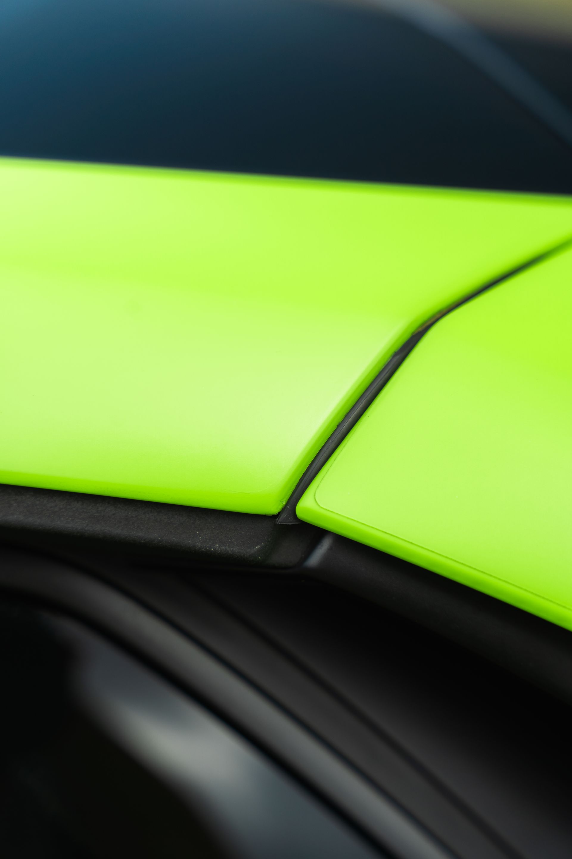 Close-up of a bright lime-green car panel with black trim and seams