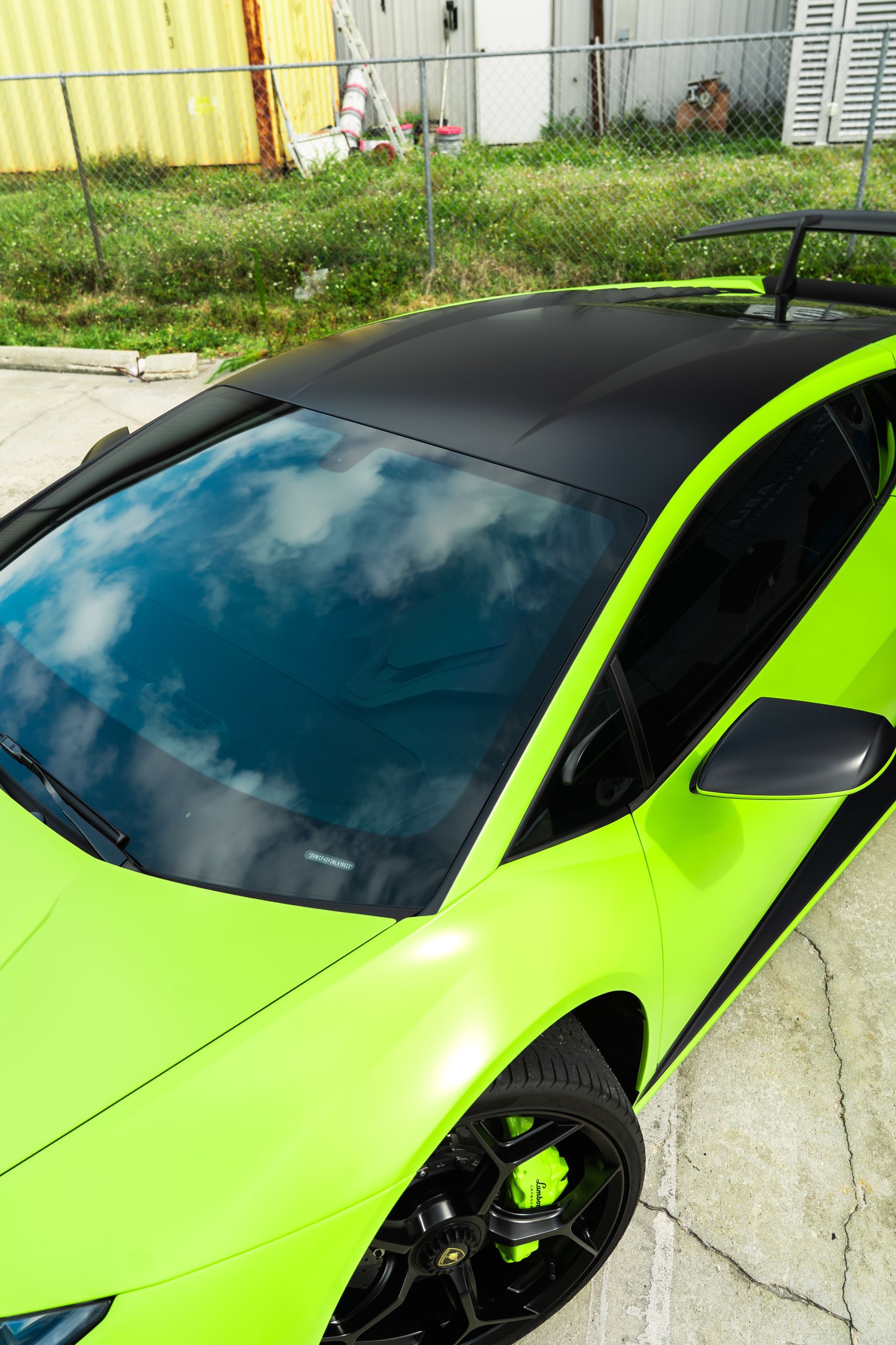 Bright neon green sports car with a black roof parked on a driveway.