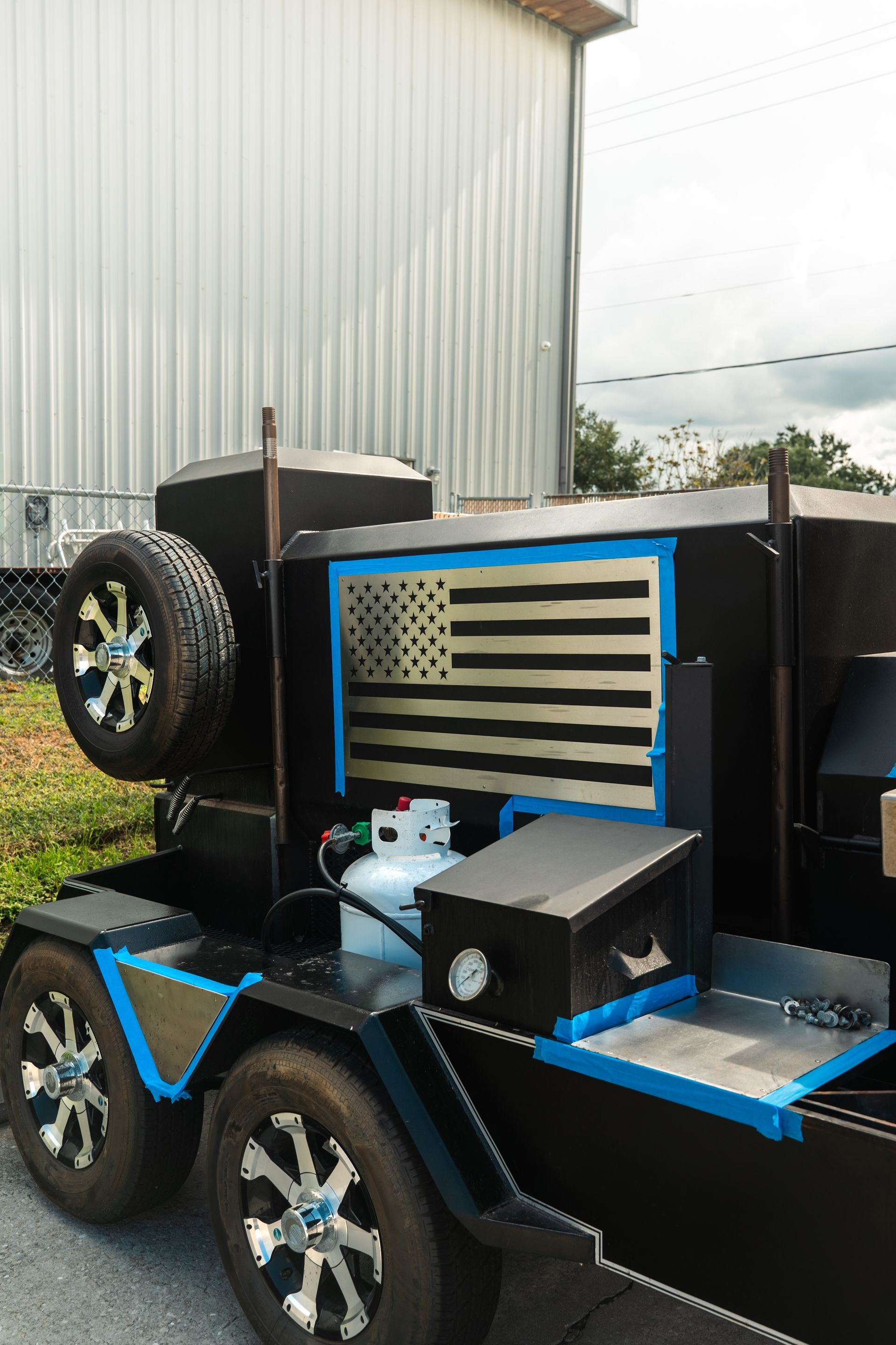 Customized black and blue off-road vehicle with chrome wheels parked beside a building