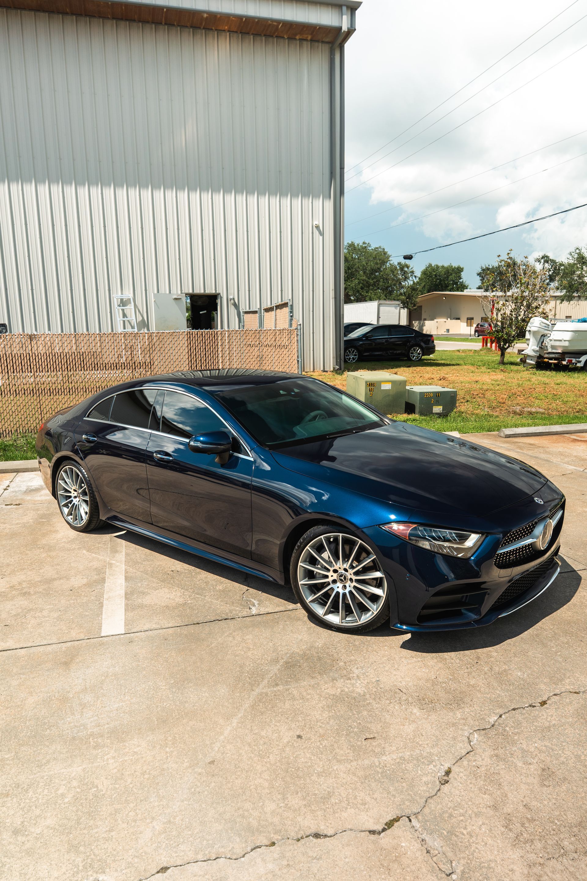Black sports coupe parked beside a corrugated metal building on a sunny day