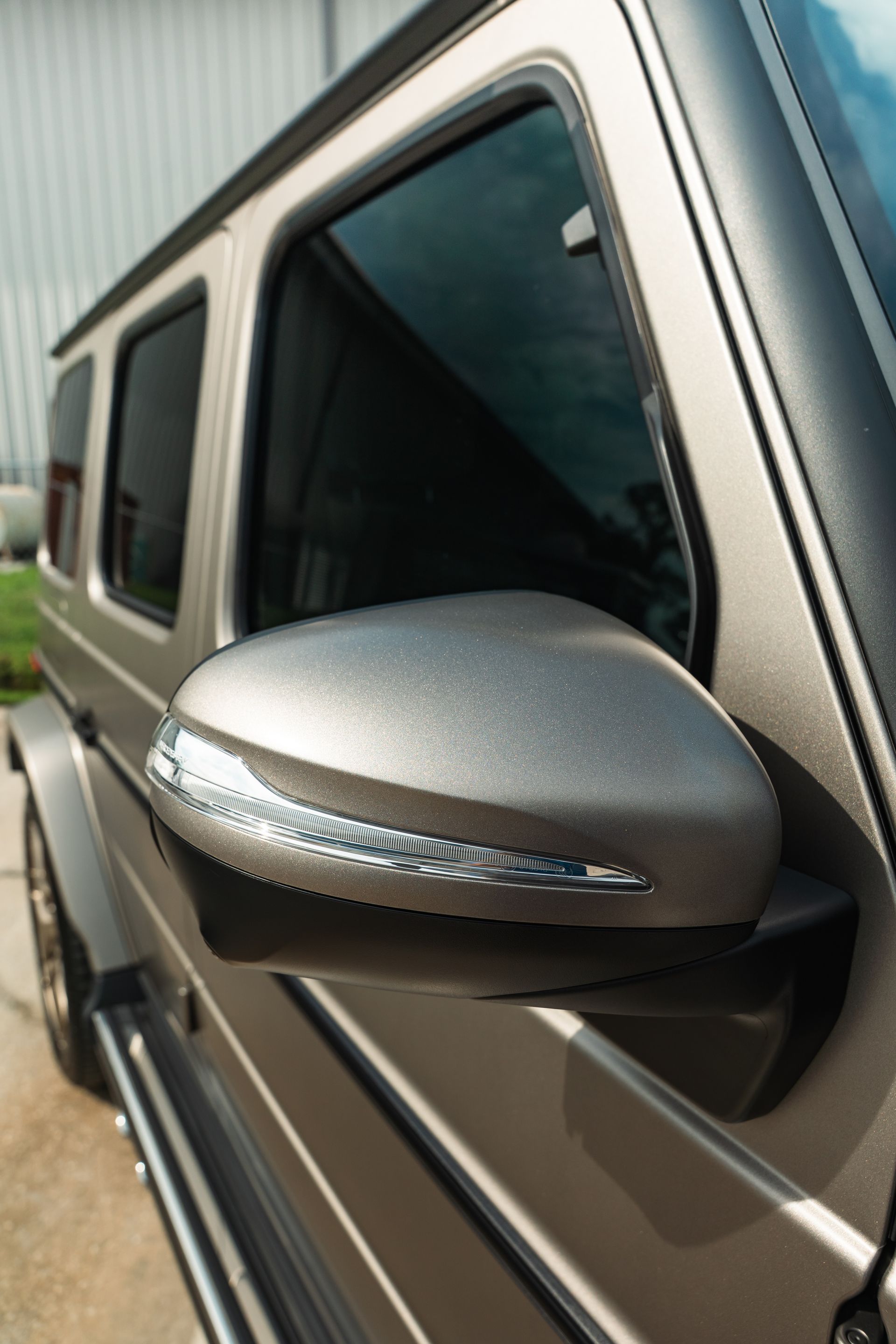 Close-up of a silver car side mirror and window on a vehicle body.