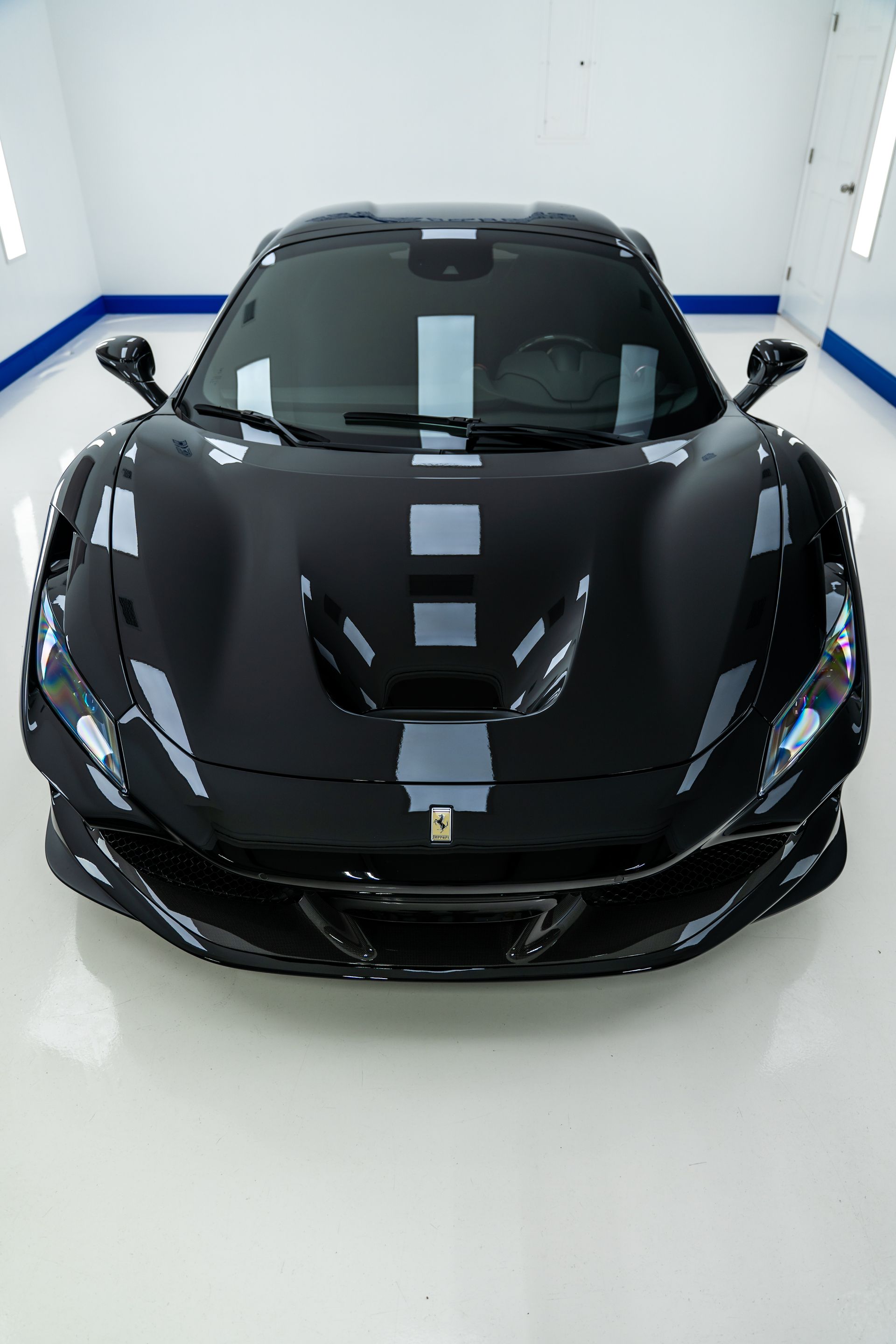 Black sports car in a white showroom with blue wall trim.